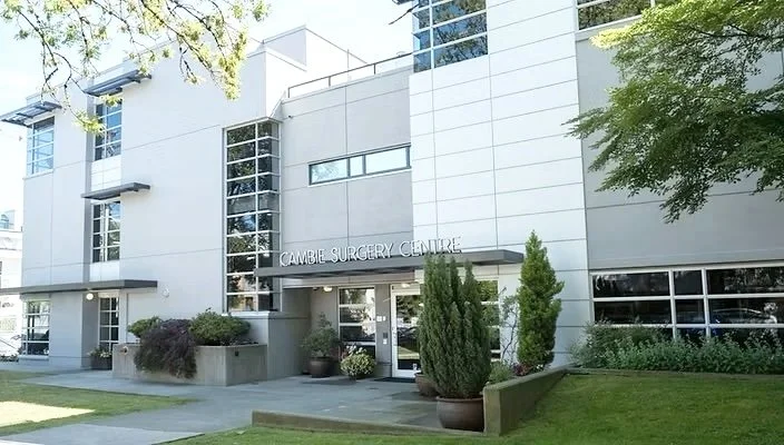 Exterior of a modern medical building with the sign 'Cambar Surgery Centre,' featuring large windows and landscaped surroundings.