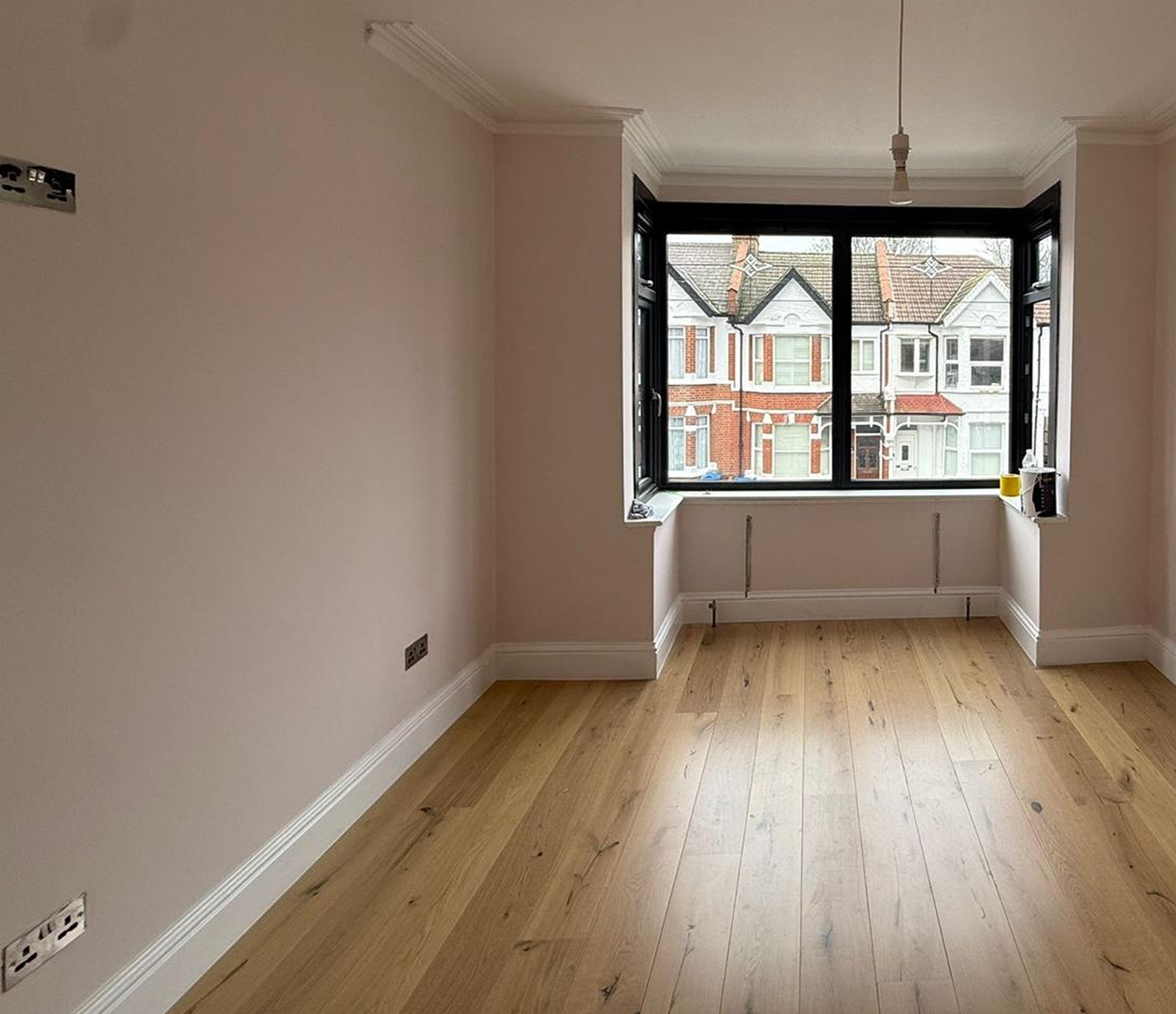 Empty room with large window, bare walls, and hardwood floor.
