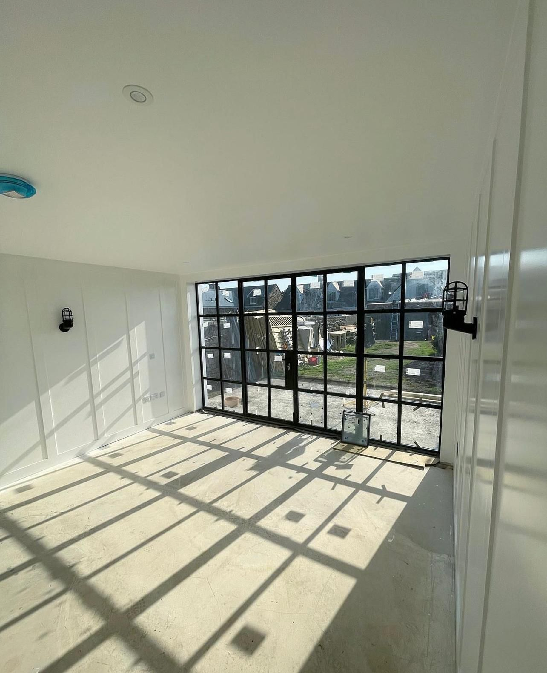 Interior of a house under construction with large window casting shadows.