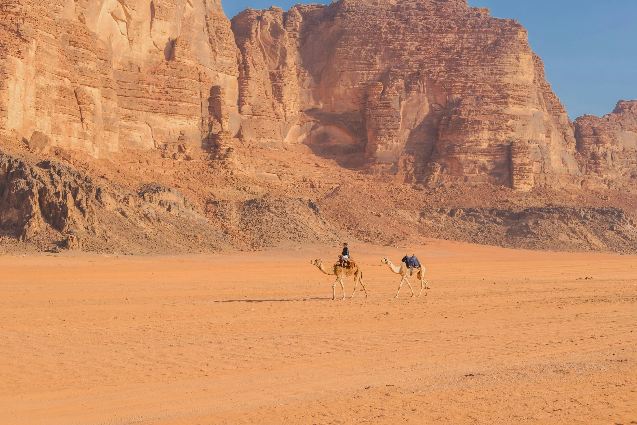 Two travelers standing before the towering red rock formations of Petra, Jordan, a feature of Holyland Horizons extension tours.