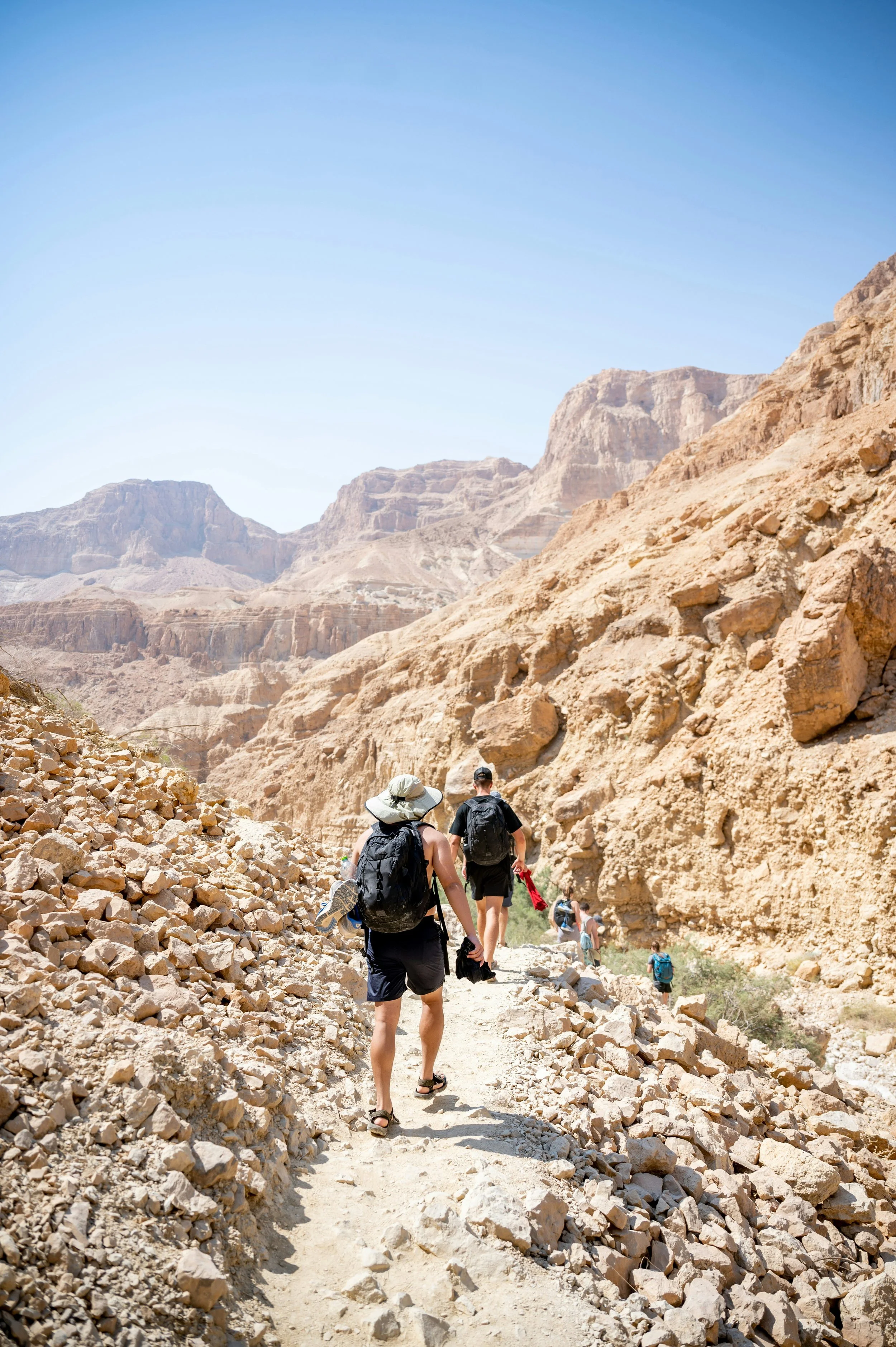 Group of hikers walking along a rocky path through a canyon in Israel's desert landscape.