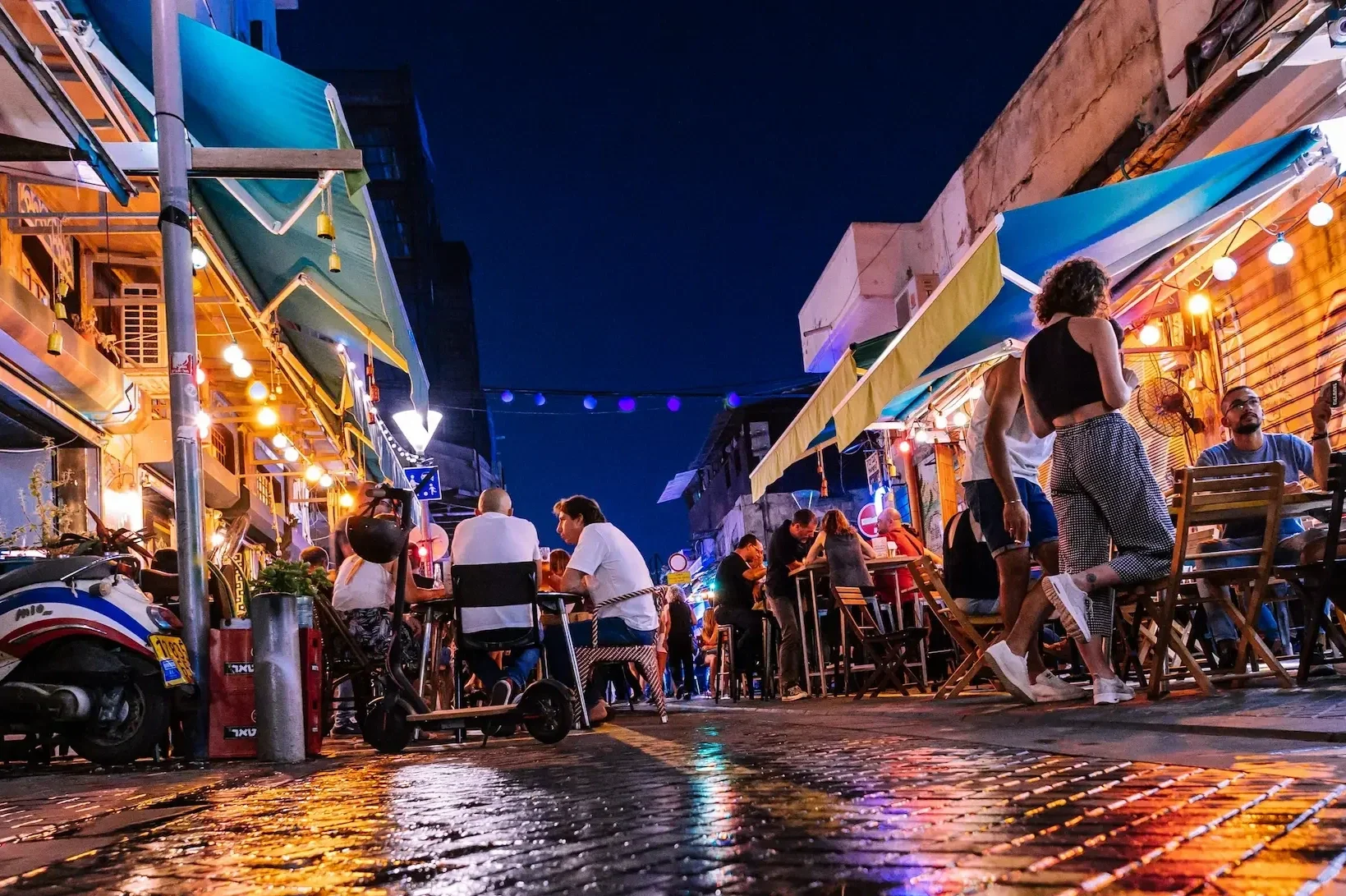 Visitors dining at outdoor tables on an illuminated street in Jerusalem at night during a Holyland Horizons After Dark experience