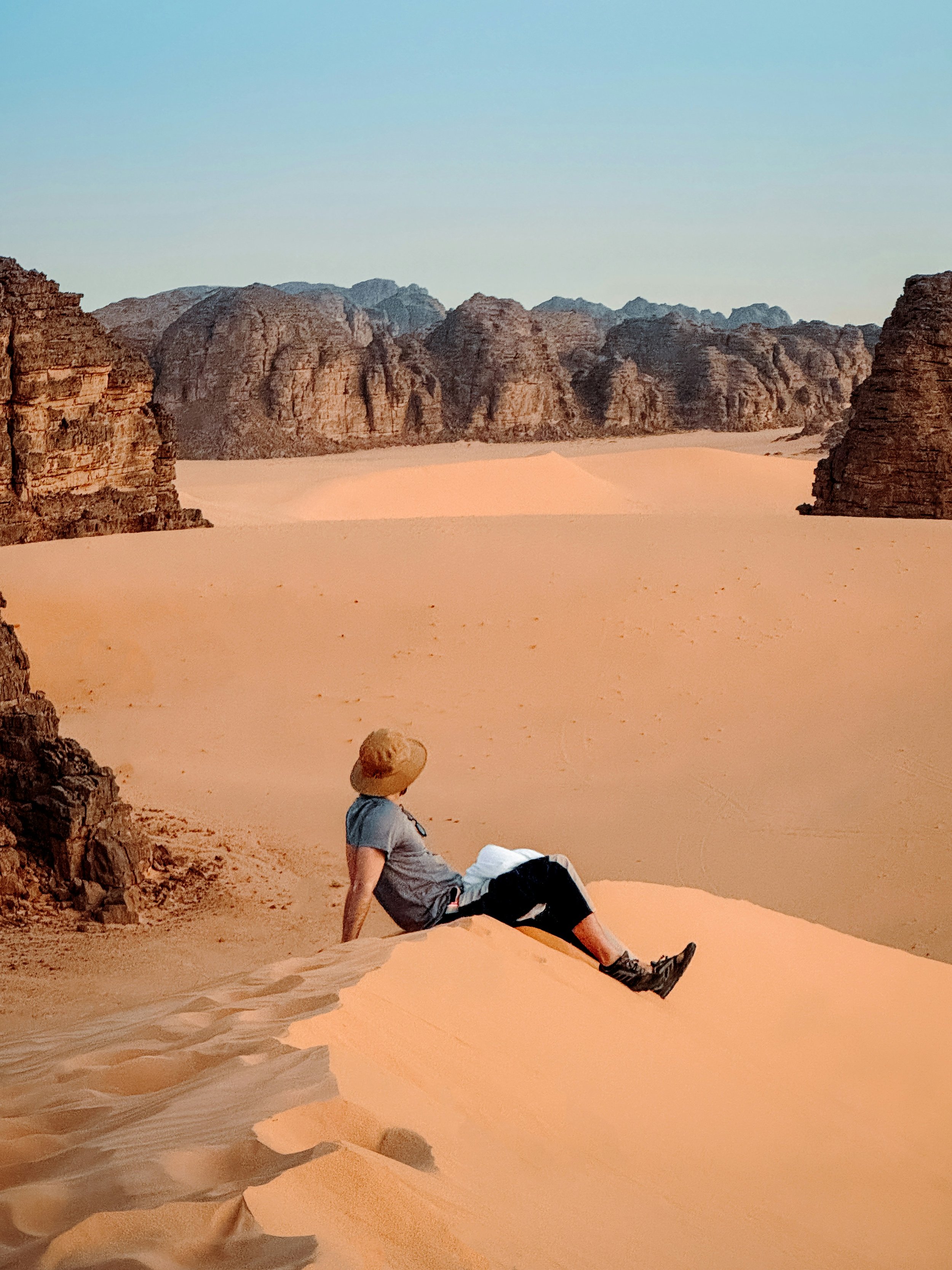 Traveler in a sunhat sitting on vast sand dunes in Wadi Rum, Jordan, on a Holyland Horizons Jordan extension tour