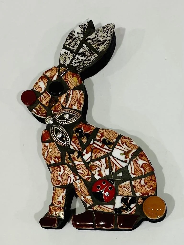 Decorative cat-shaped wall art made of patterned fabric, black frames, and embellishments like beads and stones on a white background.