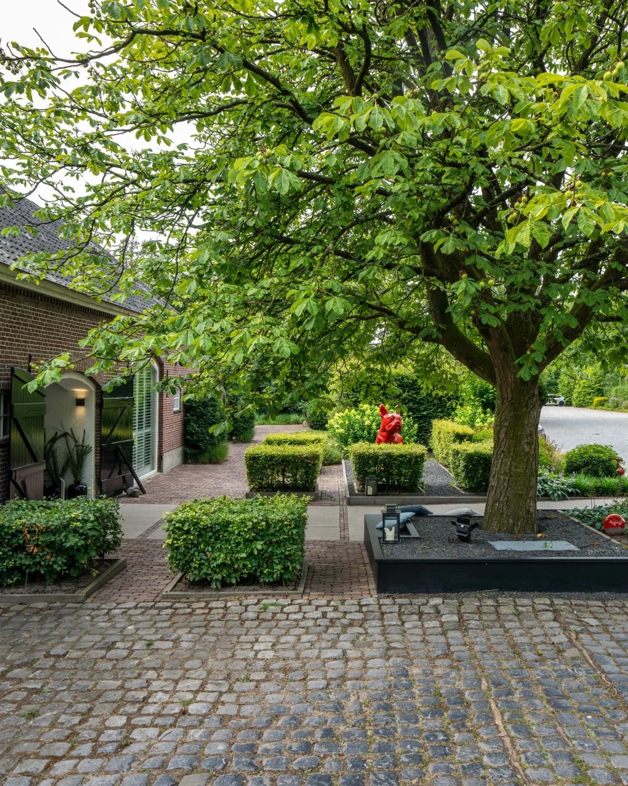 Een zorgvuldig vormgegeven entree leidt gasten op een natuurlijke wijze de tuin en het restaurant binnen. Strak, groen en uitnodigend.