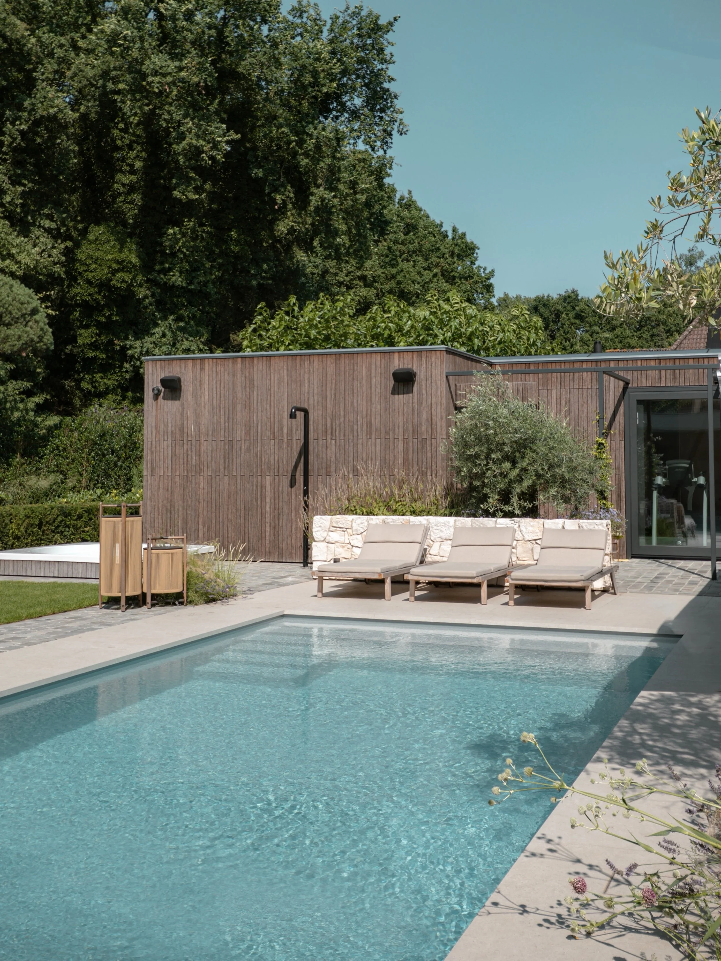 Het zwembad, de Drop Spa en de buitendouche vormen samen een rustige plek voor ontspanning. 

De houten wand van bamboe biedt beschutting en voegt tegelijkertijd warmte toe aan het ontwerp.

Een luxe buitenbeleving waarin functionaliteit en sfeer sam
