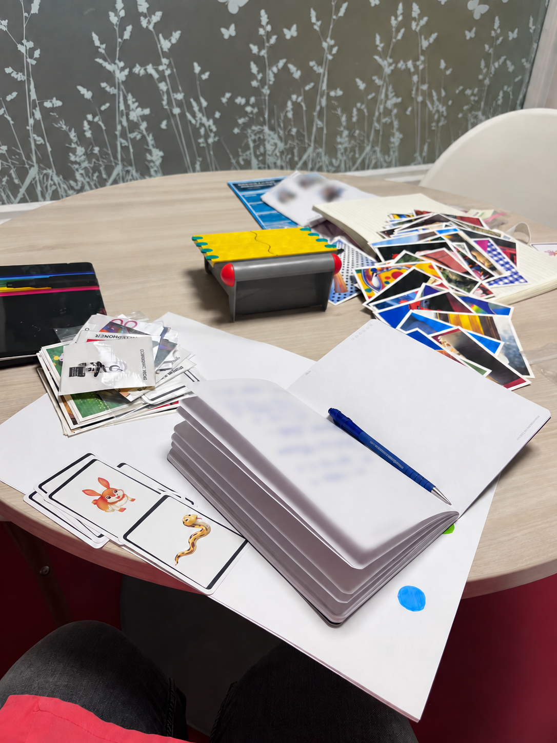 Bureau avec des cartes, un carnet, un stylo, et des photos empilés, utilisé pour une création de jeu en CAA
