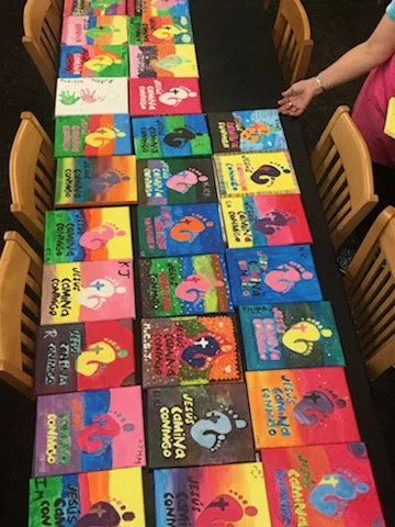 Colorful children's books with flamingo and animal illustrations arranged on a table, with a child reaching for one.