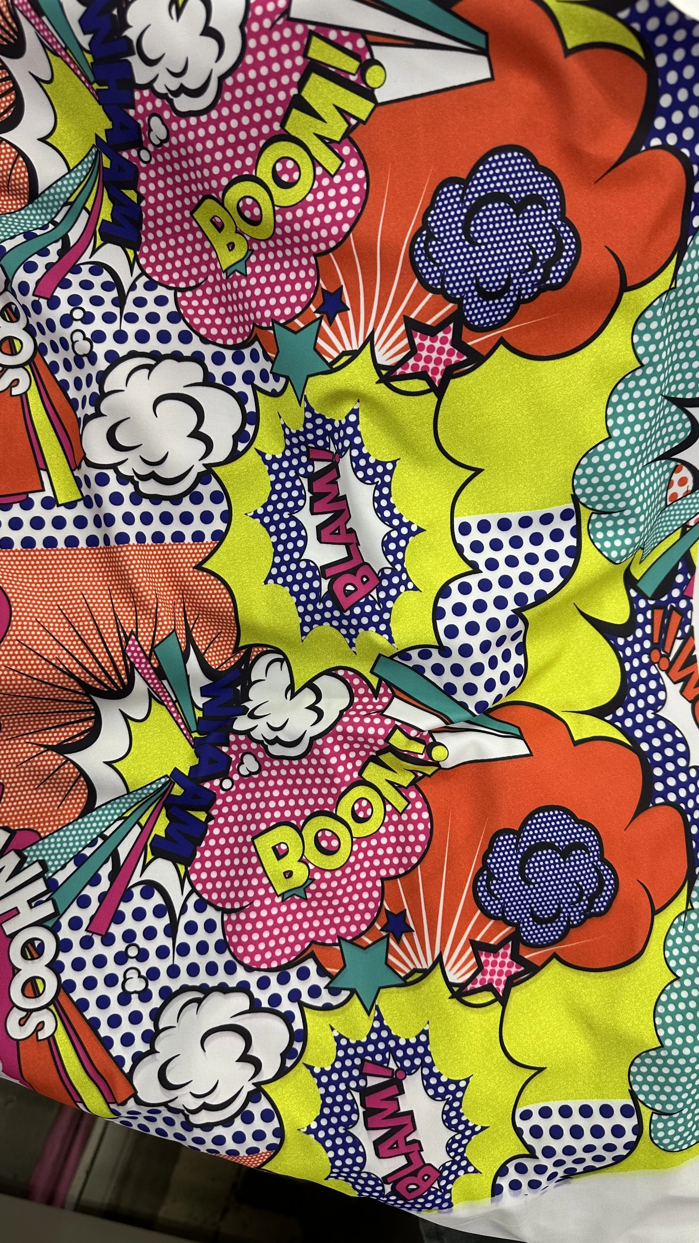 Colorful comic book style pattern with words like 'BOOM!' and 'BLAM!' in bright colors, surrounded by clouds and starburst designs.