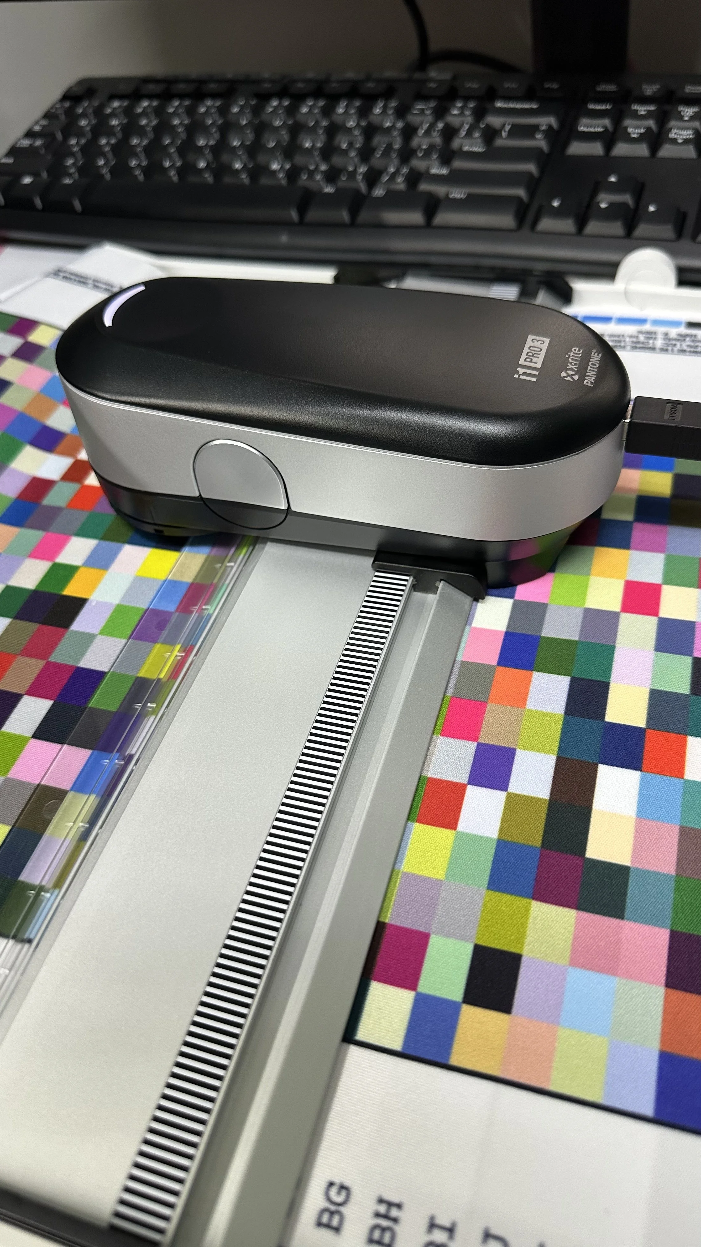 A spectrophotometer measuring colors on a color chart with a computer keyboard in the background.