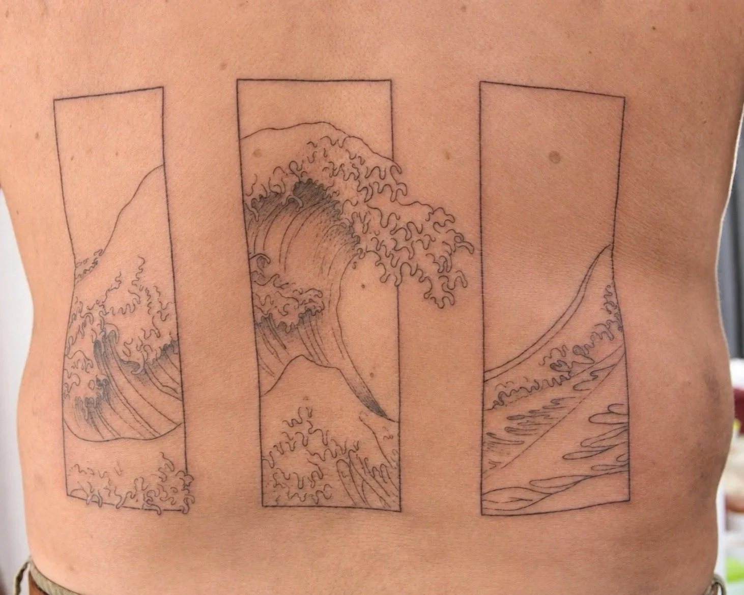 Fine line 'The Wave' tattoo in a stylised way