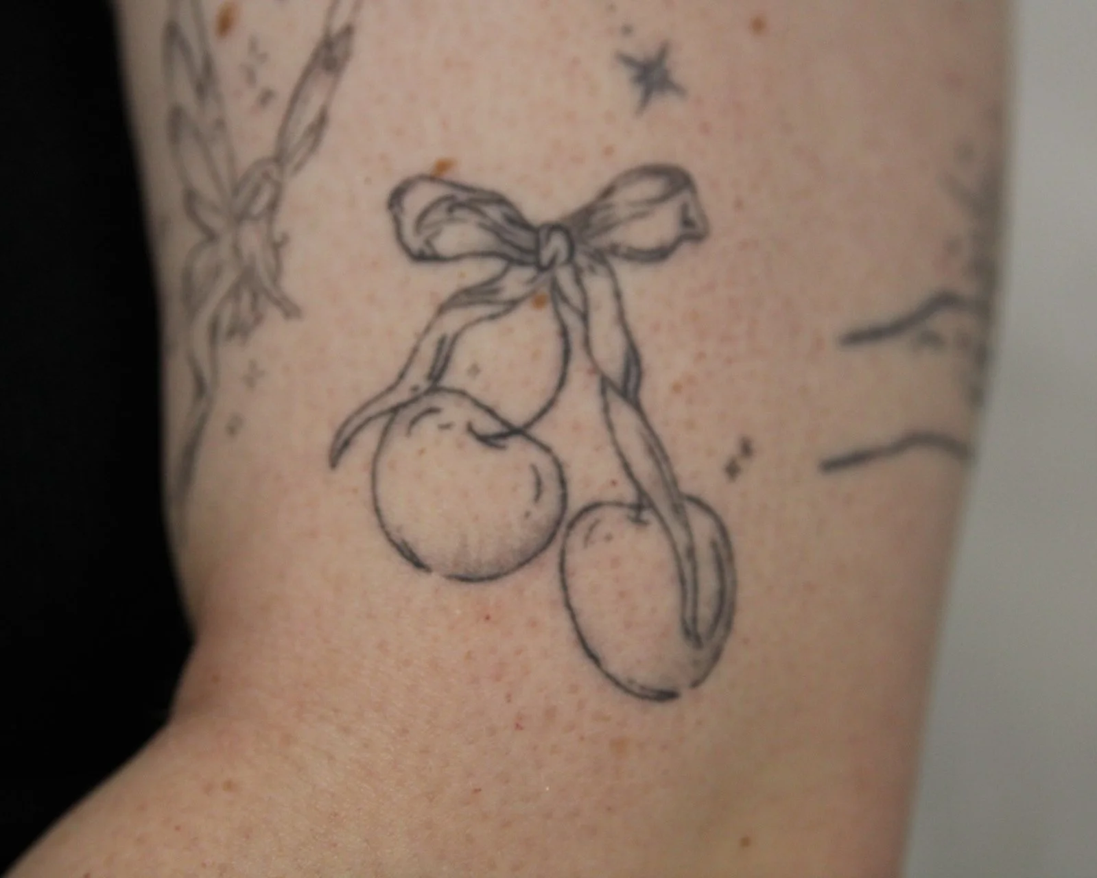 Fine line cherrys and sparkles tattoo
