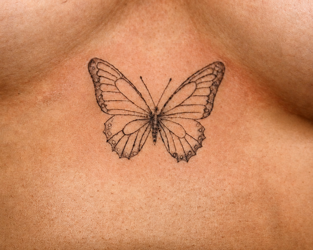 Fine line butterfly tattoo on sternum