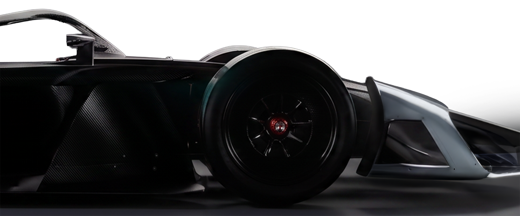 Close-up of a black Formula E GEN4 race car with carbon fibre details and aerodynamic design, showing the front wheel and part of the body in a studio setting.
