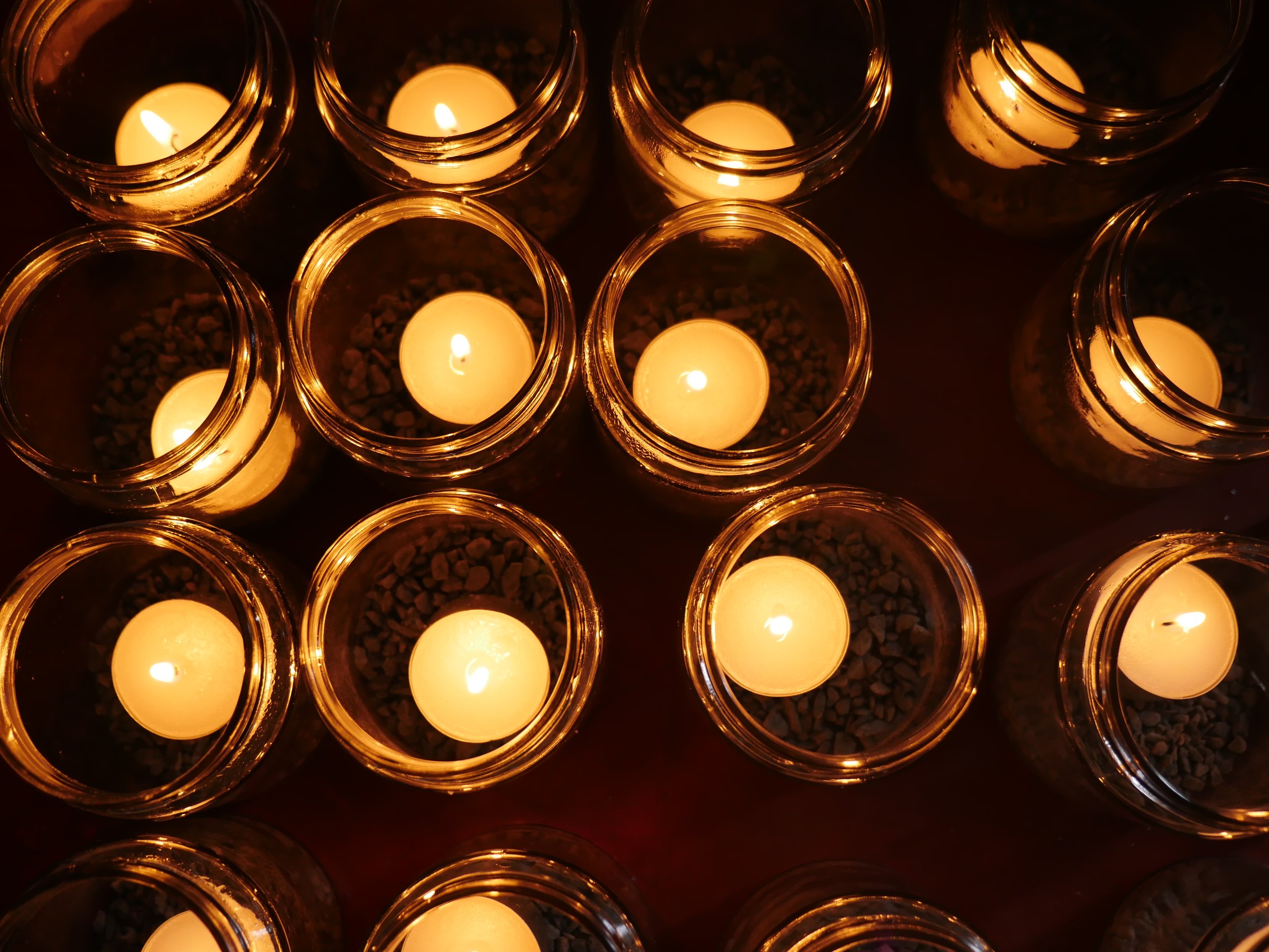 Multiple glass jars containing lit candles viewed from above, creating a warm, glowing ambiance.