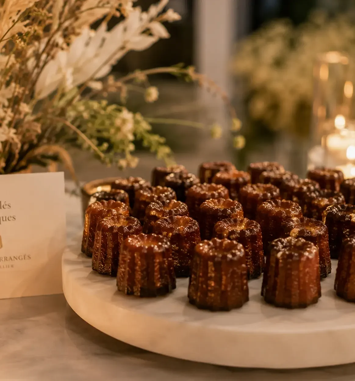 Assortiment de canelés classiques présenté sur un plateau dans une ambiance chaleureuse