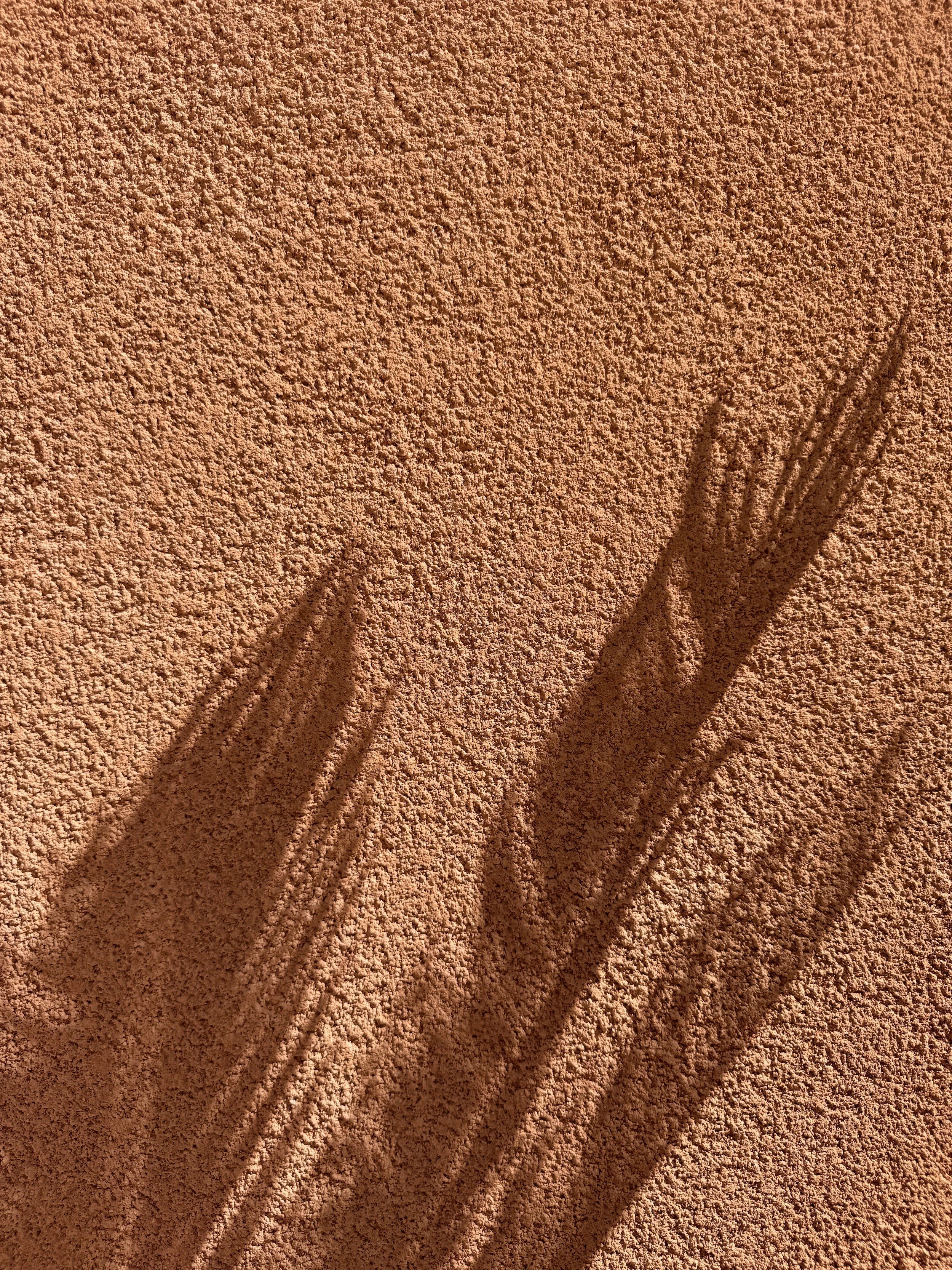 Close-up of textured terracotta-colored surface with shadows.