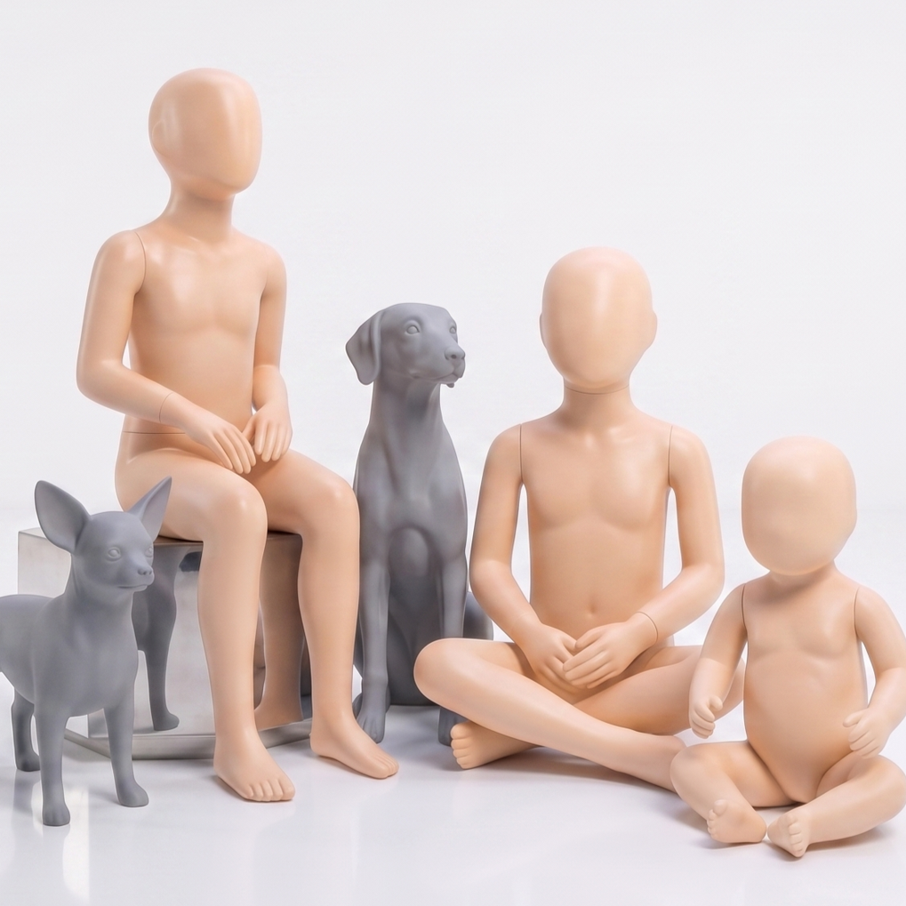 İki bebeğin ve iki köpeğin figüratif heykelleri, hepsi çıplak ve yüzleri yok. Heykeller gri ve bej renklerinde, çıplak çocuklar oturuyor ve köpekler yanlarında duruyor. Arka plan beyaz.