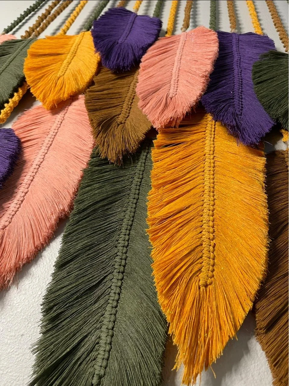 Colorful decorative fringe tassels in pink, purple, yellow, brown, and green hanging in a pattern.