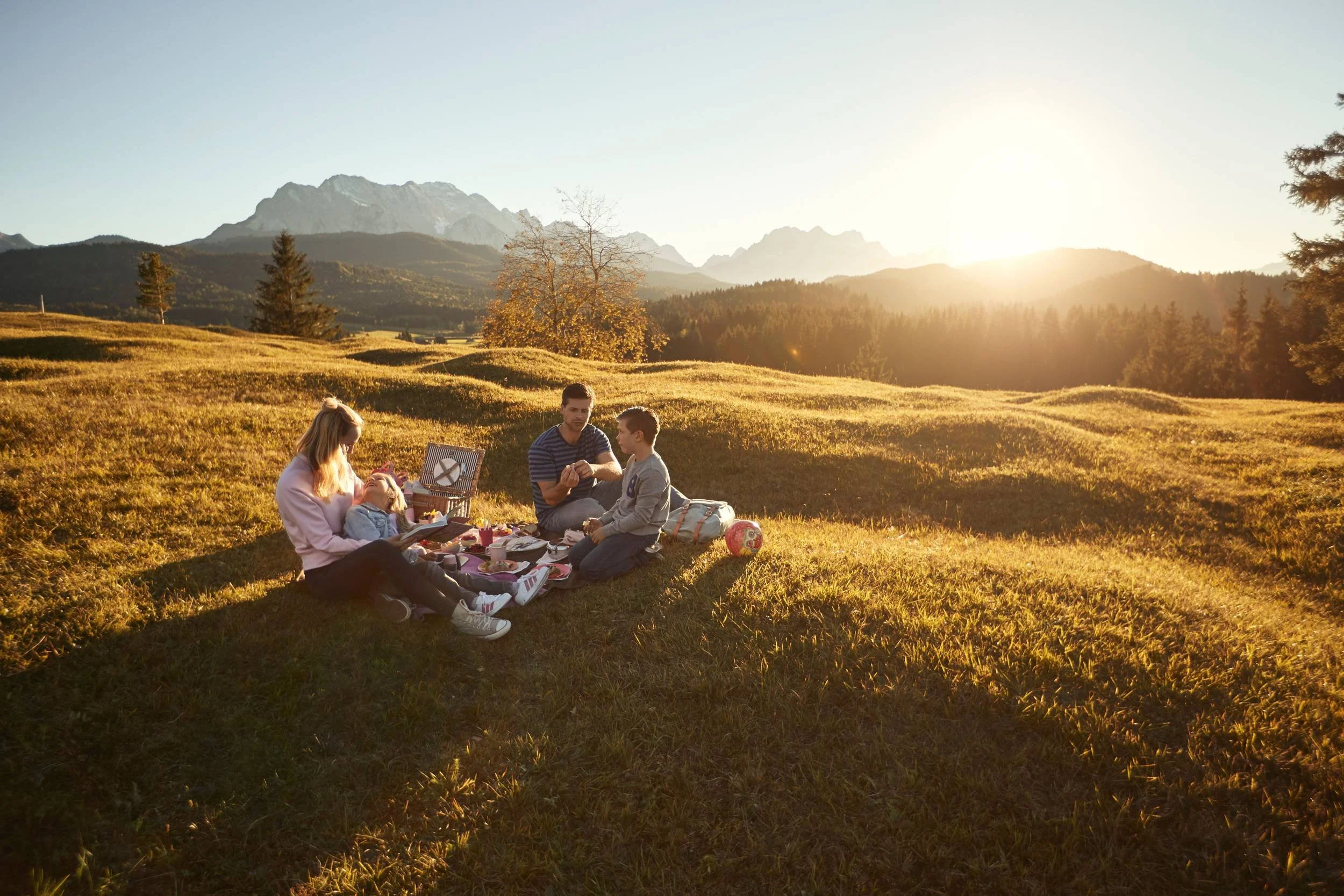 Familienpicknick auf Almwiese im goldenen Abendlicht