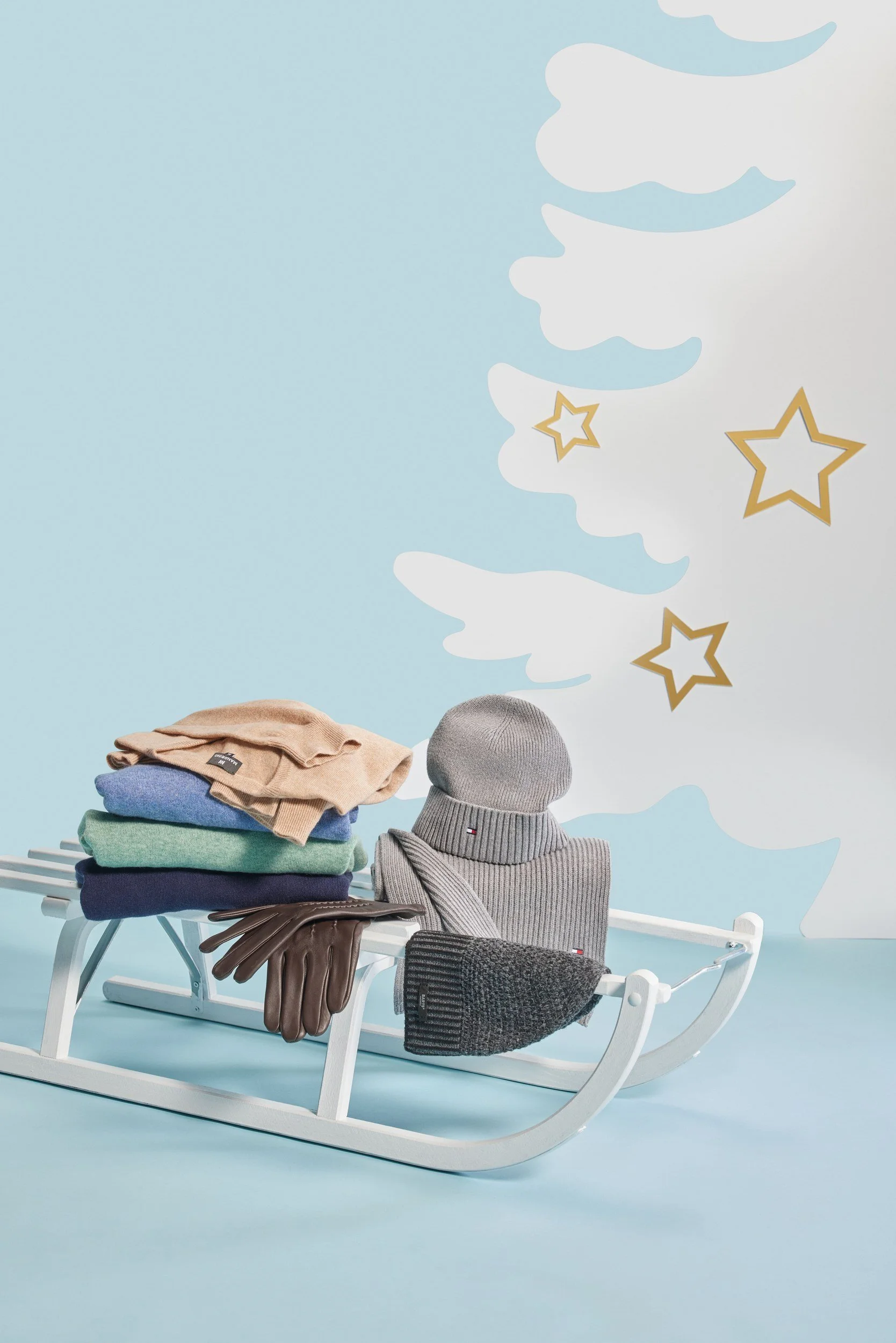 Strickstapel und Mütze auf weißem Schlitten vor Wintermotiv