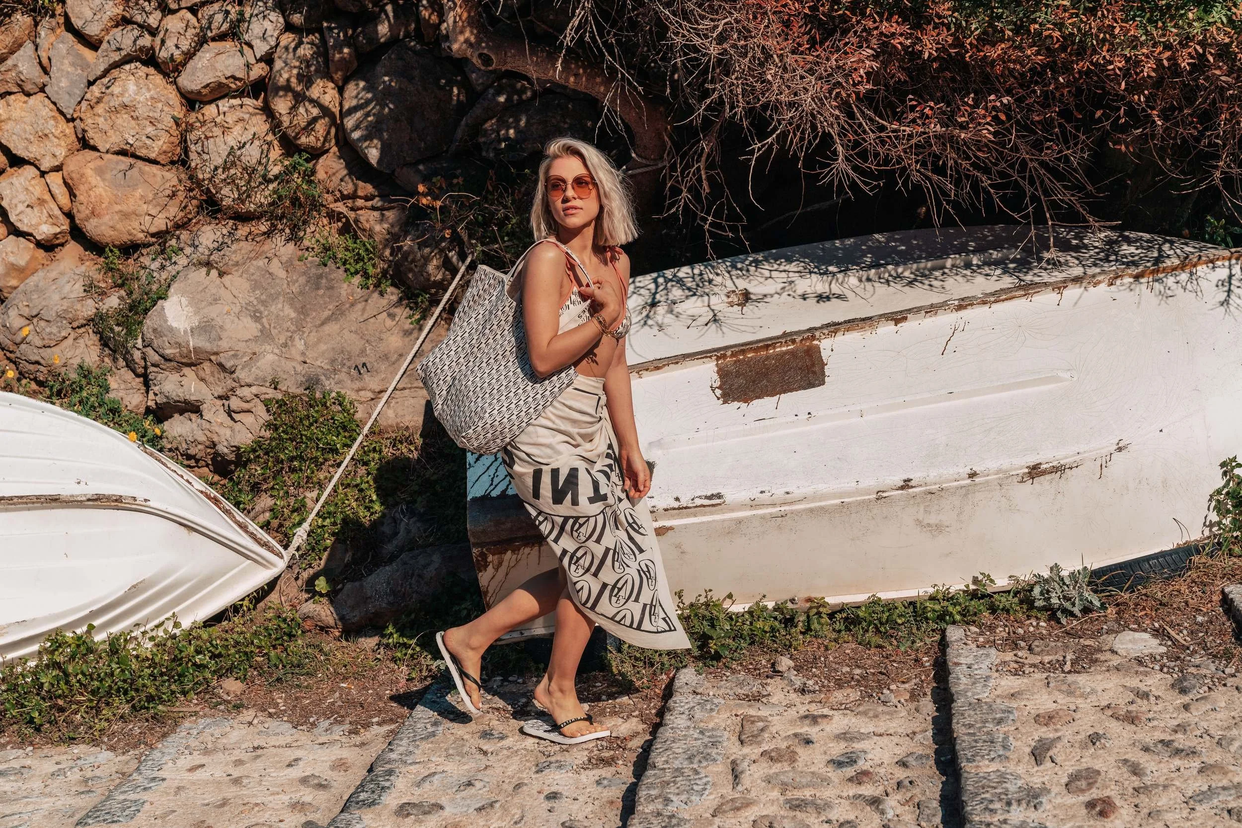 Model mit Strandtasche vor alten Holzbooten