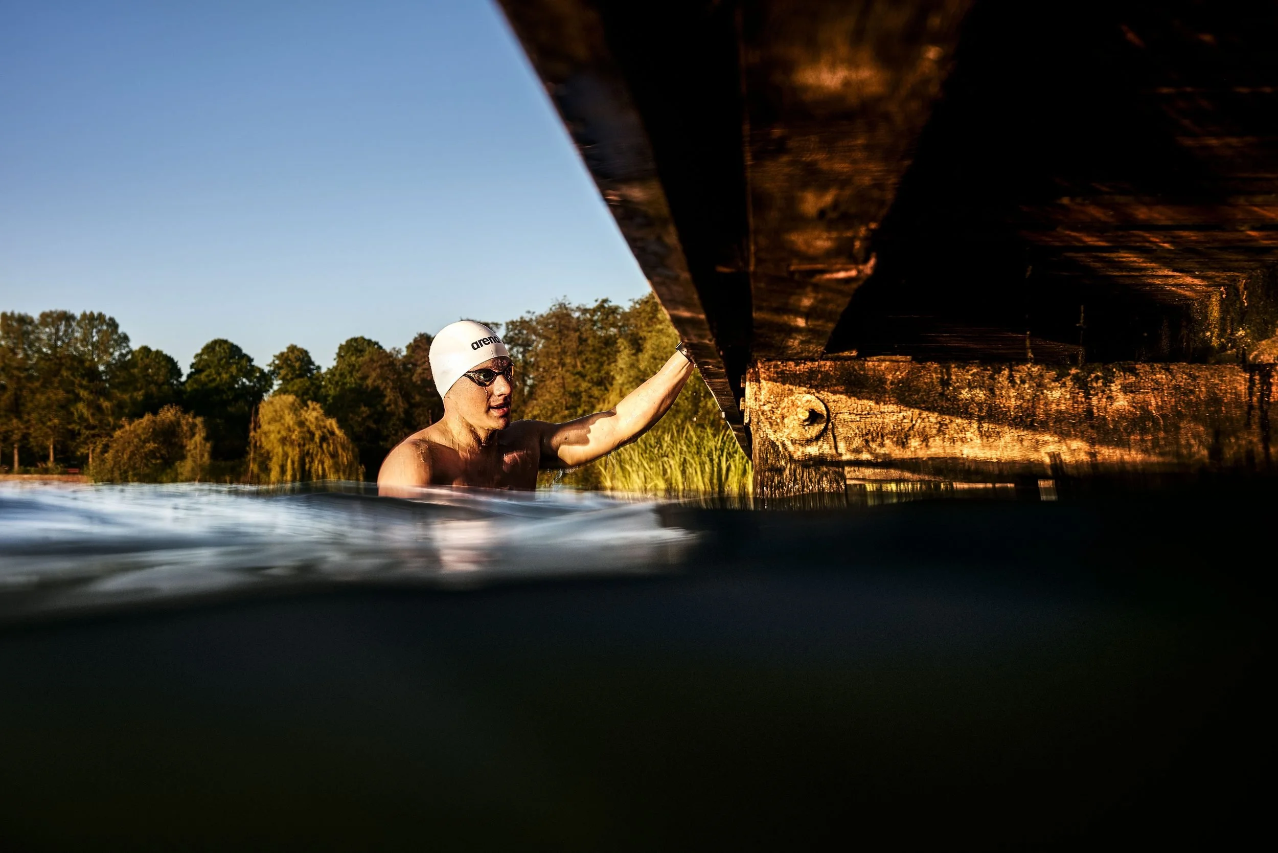 Schwimmer-Editorial von Tim Wendrich: Schwimmer im dunklen Wasser unter einer Brücke