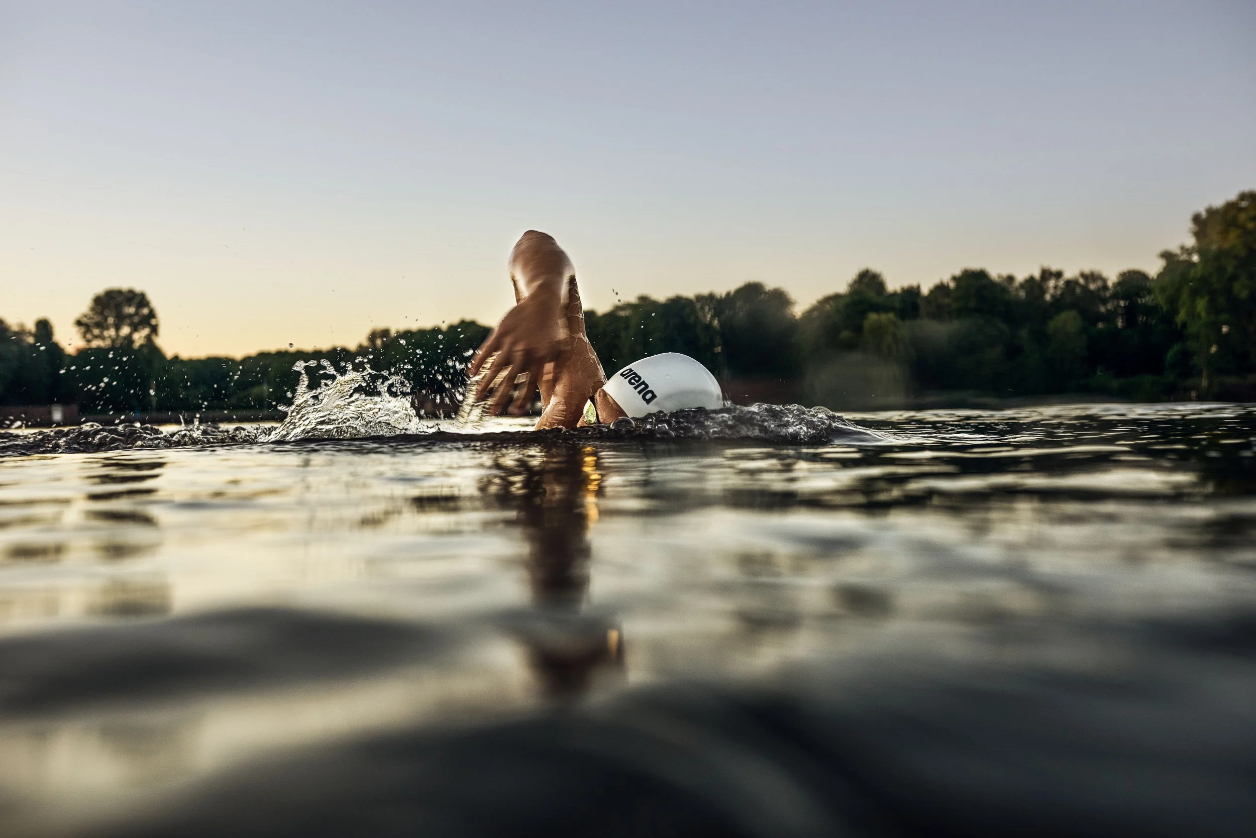 Schwimmer-Editorial von Tim Wendrich: Rückenansicht im Wasser mit aufspritzender Gischt im Gegenlicht