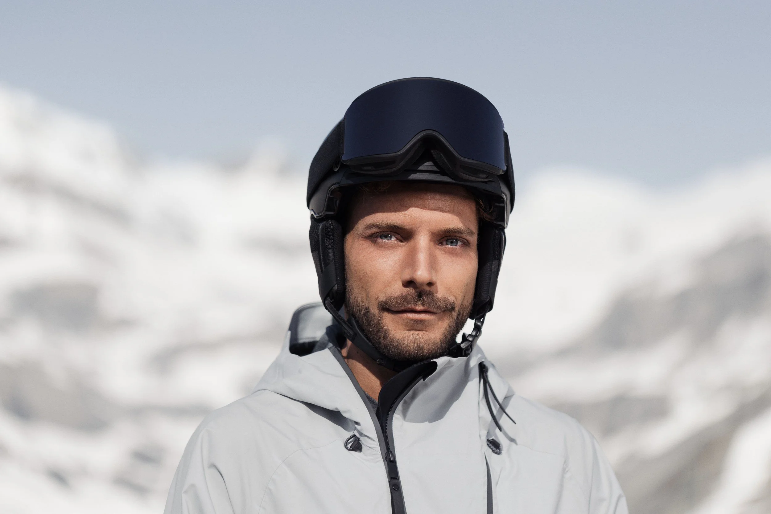 Skifahrer mit Helm und Brille vor Schneebergen