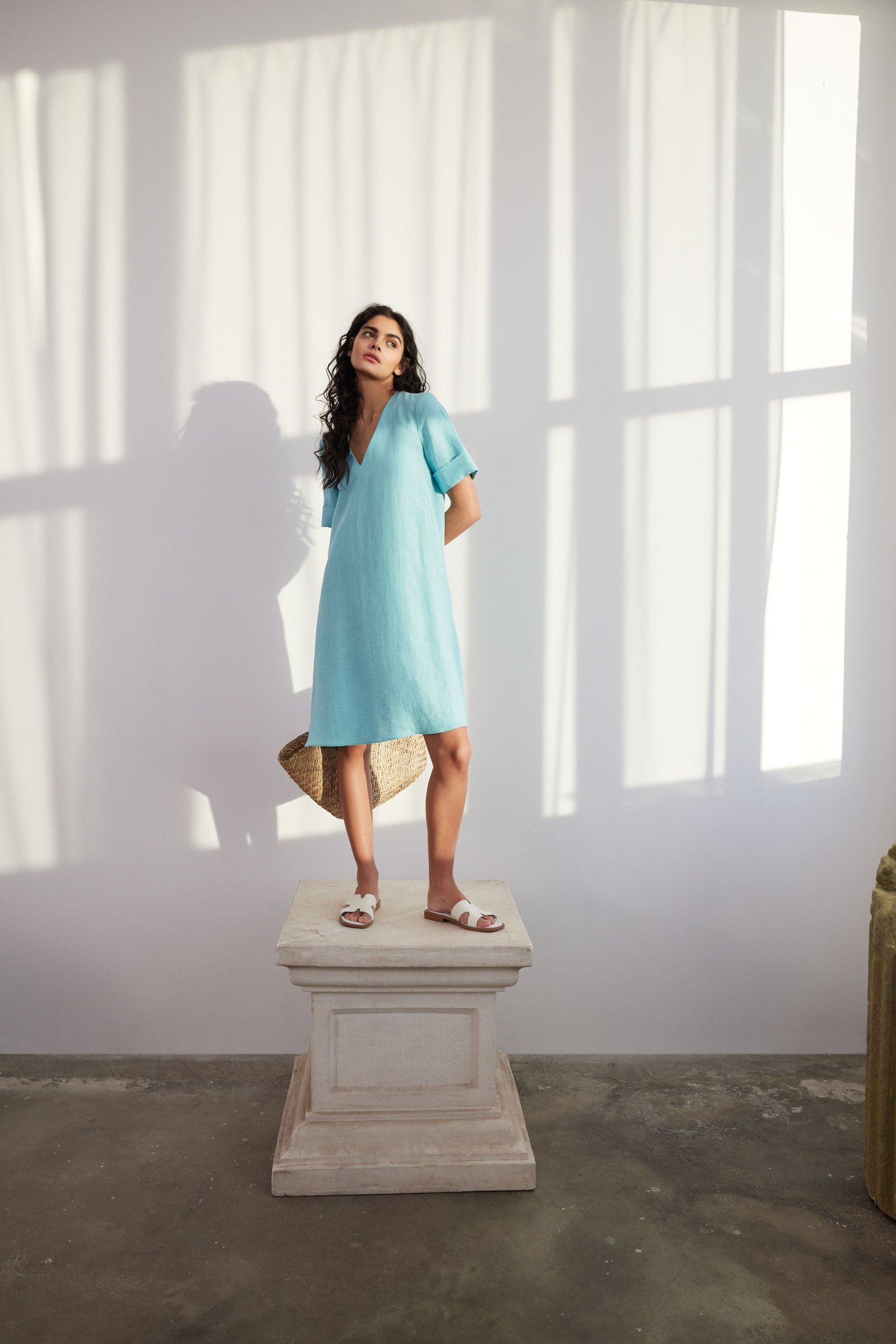 Modehaus Zinser Frühjahr-Sommer 2024: türkisfarbenes Kleid, stehend auf einem Steinsockel