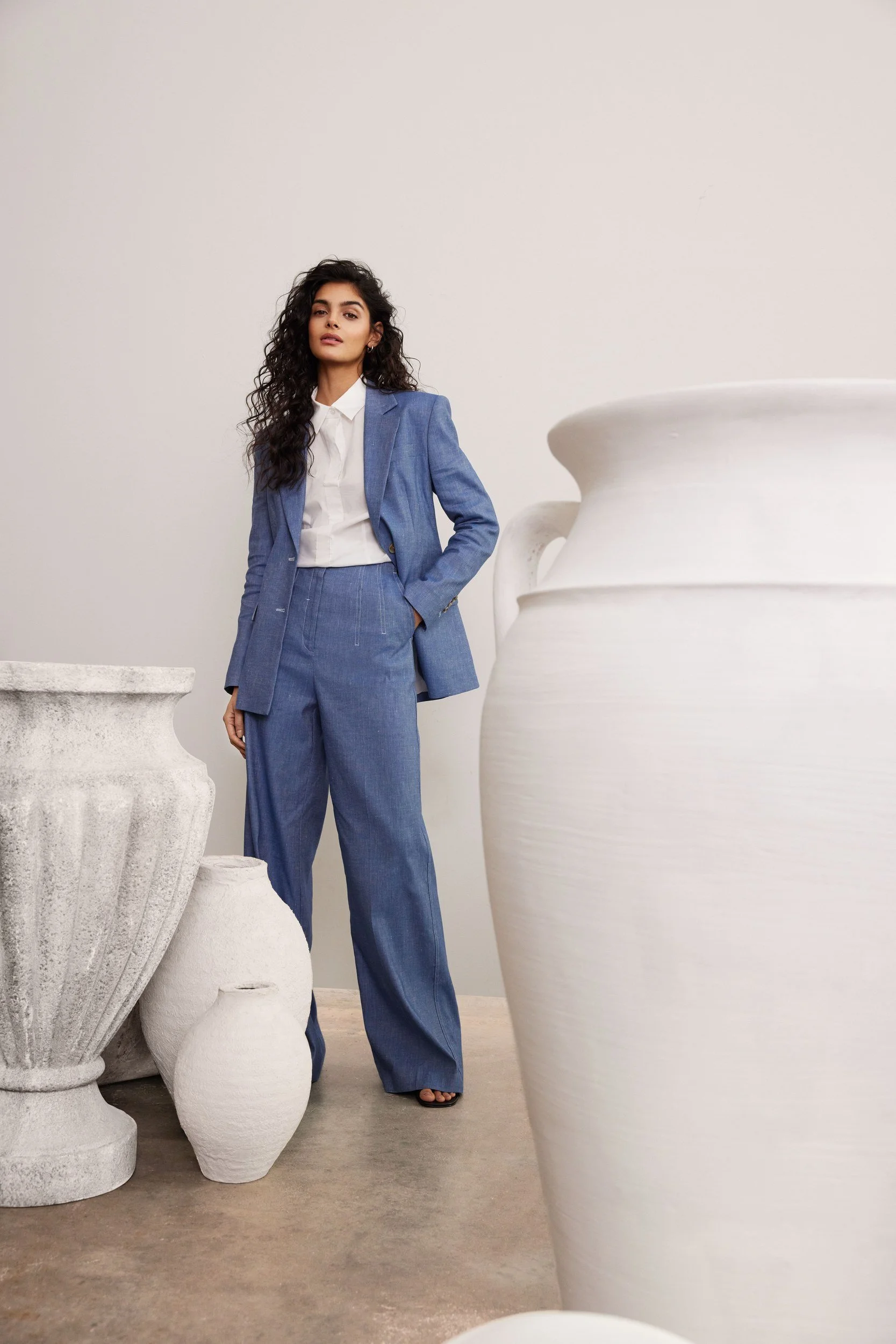 Modehaus Zinser Frühjahr-Sommer 2024: blauer Leinen-Anzug neben großer Amphore