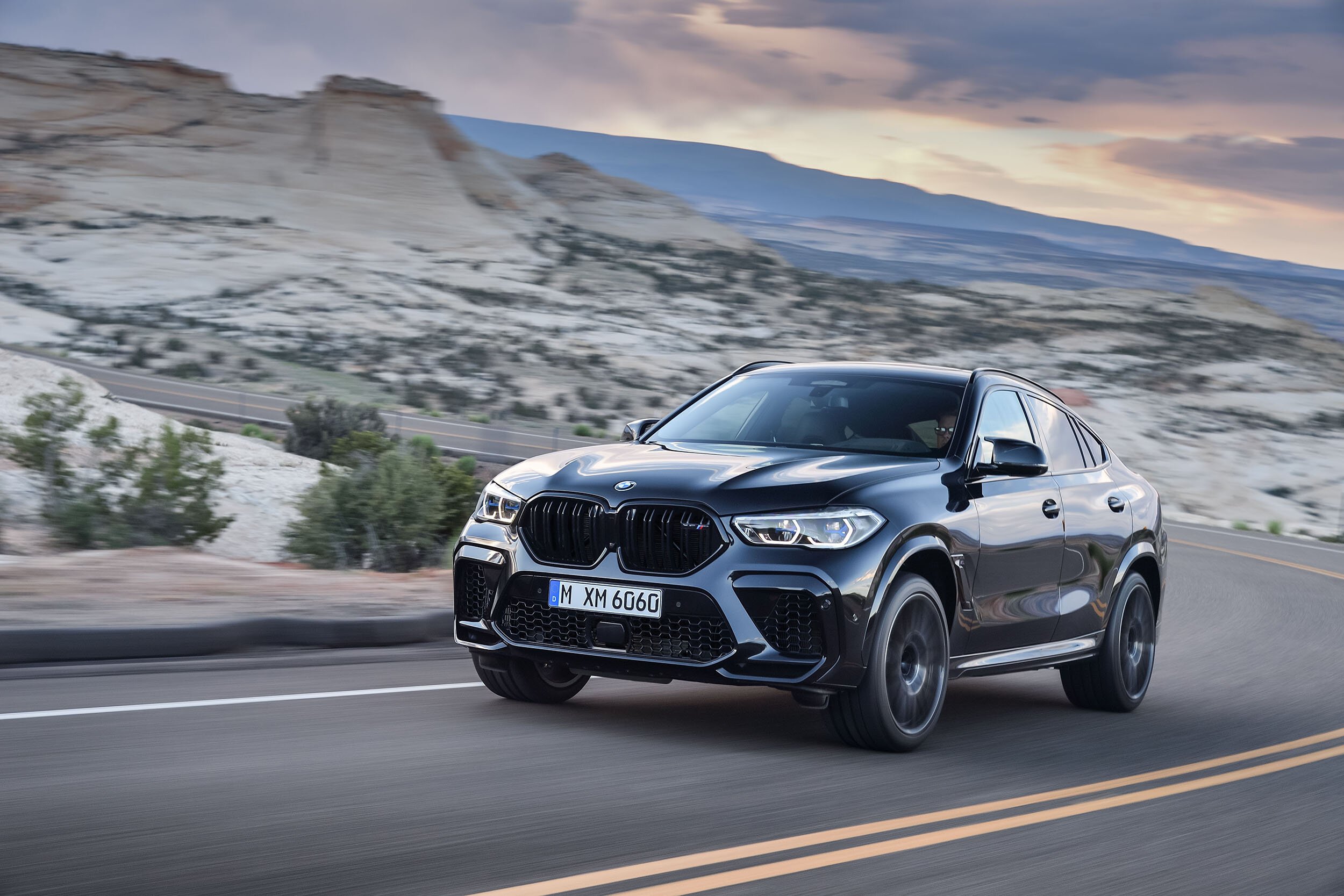 Schwarzer BMW X6M in Fahrt vor Canyon-Felsen unter Abendhimmel – High-End-Retusche von Bildergut.