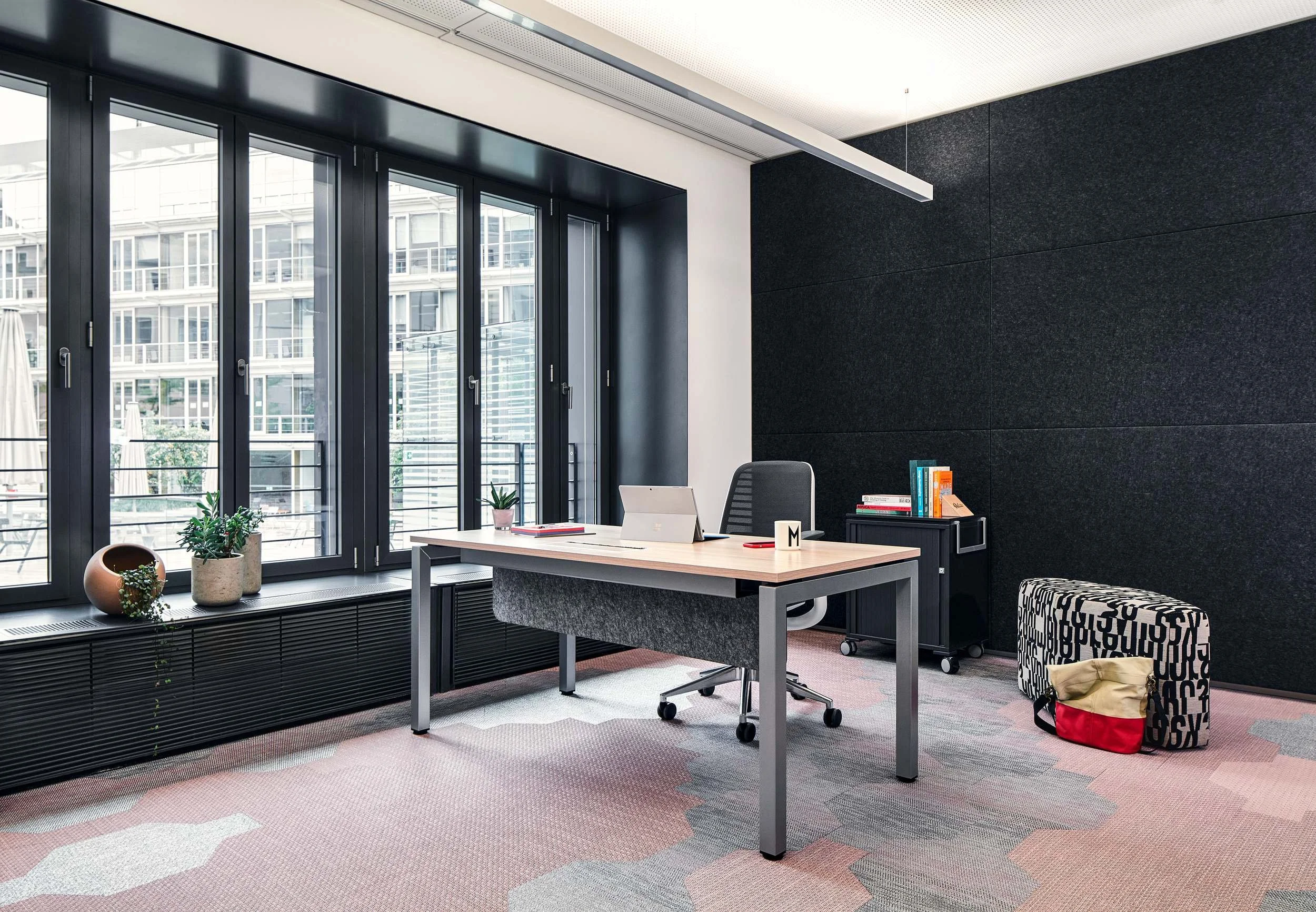 Dunkles Büro mit Steelcase Arbeitsplätzen und rosafarbenem Teppichboden
