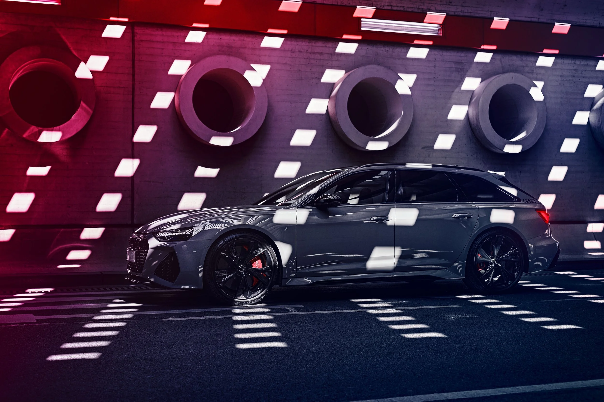 Grauer Audi RS6 Avant vor Betonwand im Spiel aus Lichtpunkten und rotem Schimmer – Look and Feel Retusche von Bildergut.