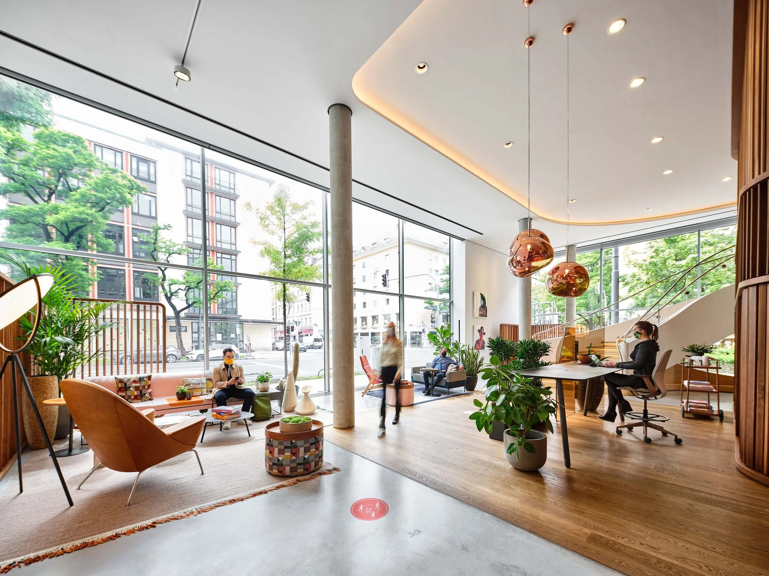 Lichtdurchflutetes Atrium mit Kupferleuchten, Pflanzen und Steelcase Arbeitsbereichen