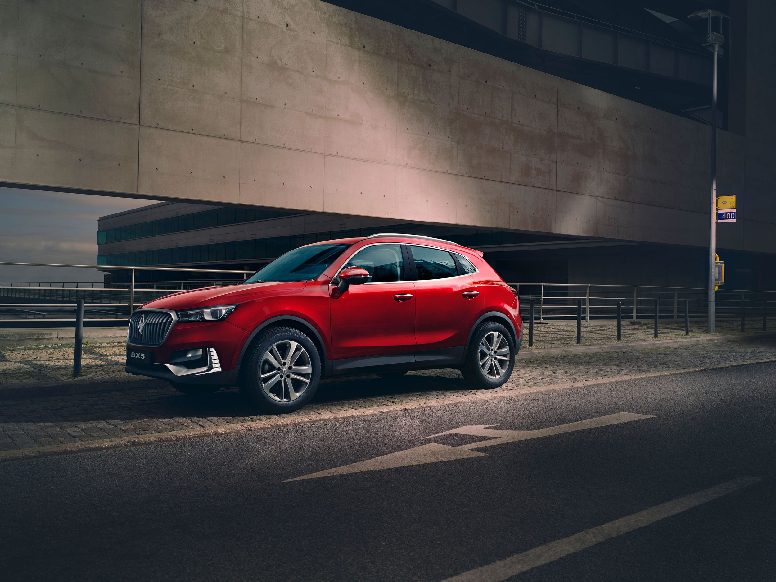 Roter Borgward BX5 SUV an Betonarchitektur bei Abendlicht am Straßenrand – High-End-Retusche von Bildergut.