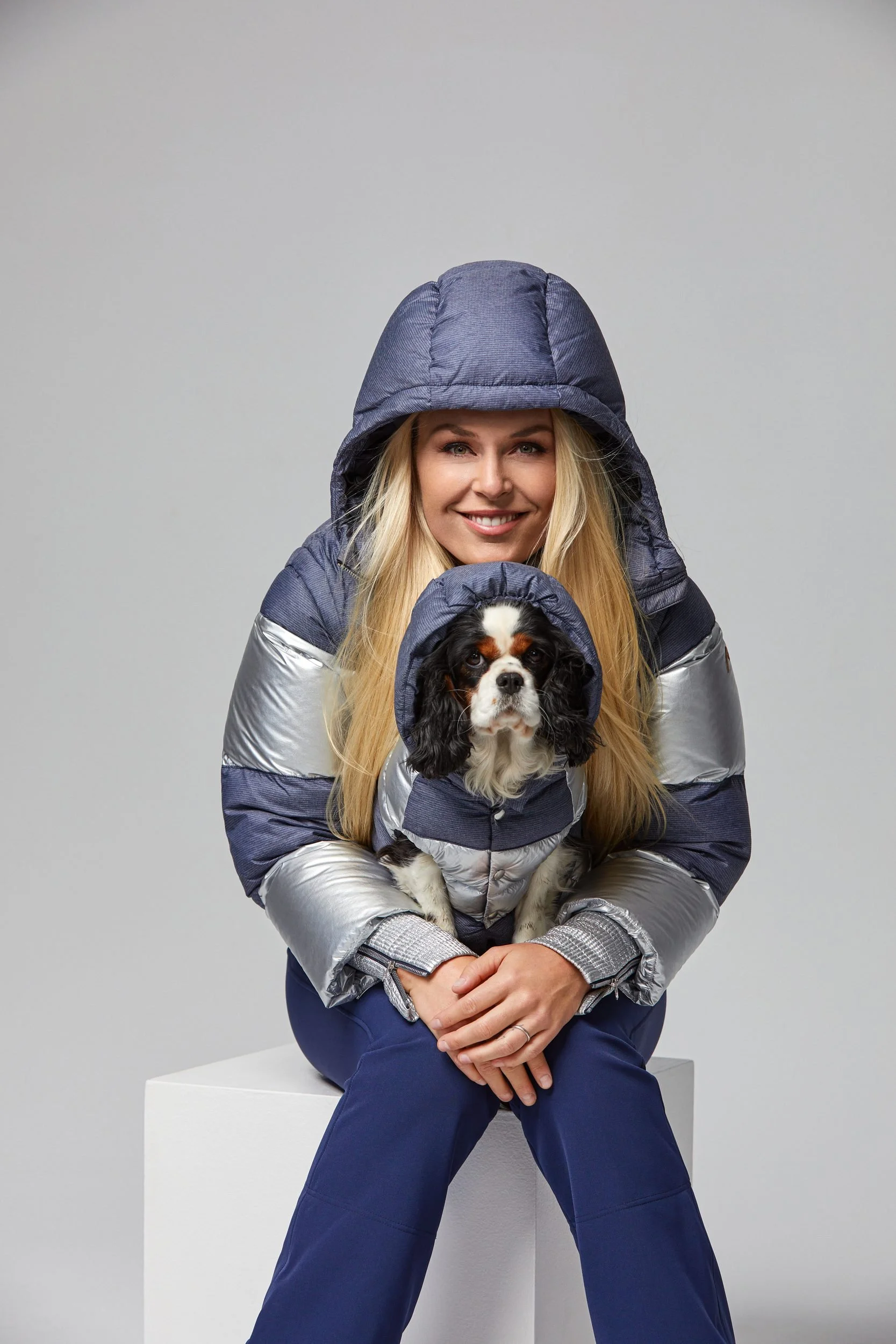 Sitzende Pose in blauer Daunenmontur mit Hund