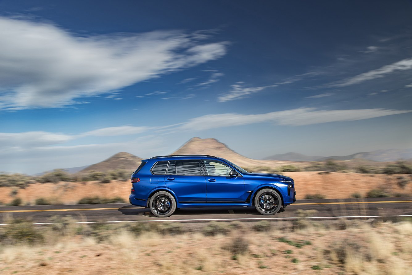 Blauer BMW X7 in Seitenansicht auf Landstraße durch weite Steppenlandschaft – High-End-Retusche von Bildergut.