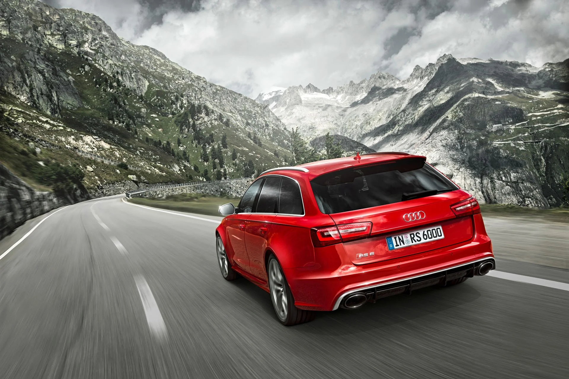Roter Audi RS6 Avant in Fahrt auf Alpenpassstraße vor schroffer Bergkulisse – Retusche Bildergut.