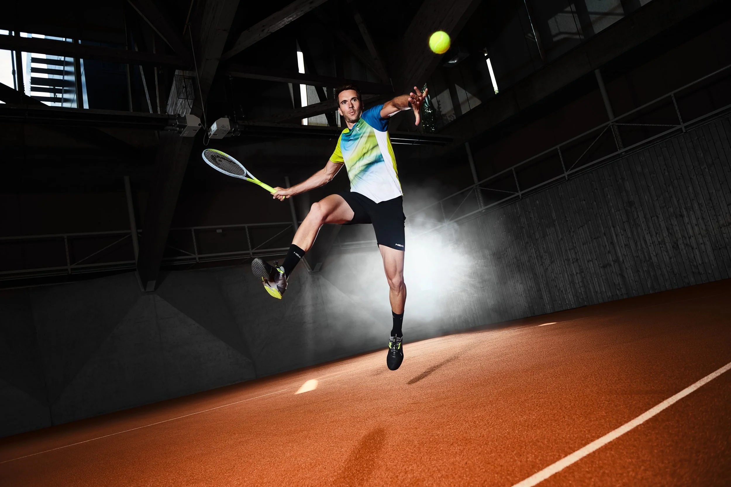 Tennisspieler beim Volley-Sprung auf dem Sandplatz in der Halle