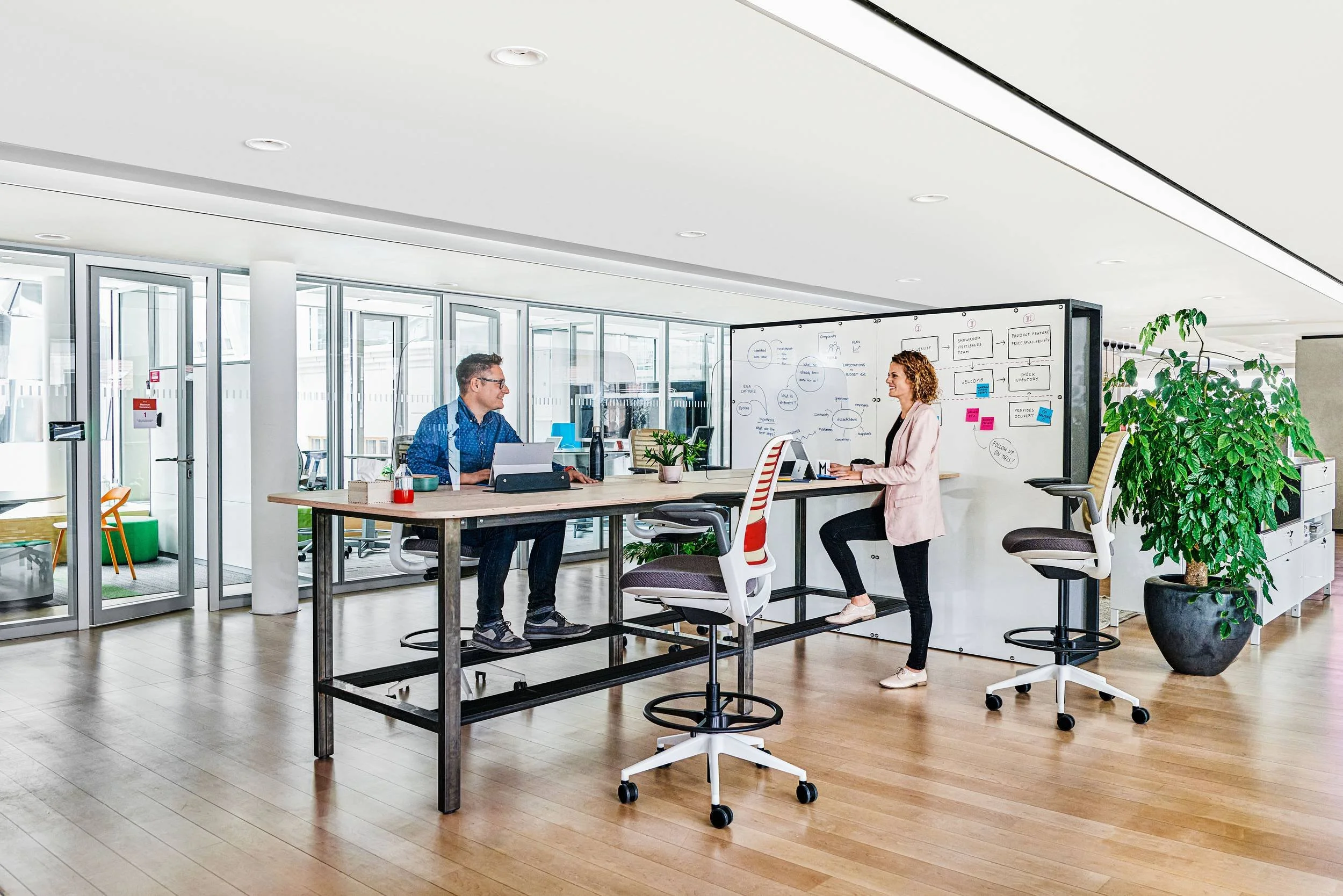 Zwei Kollegen im Gespräch am höhenverstellbaren Steelcase Arbeitstisch