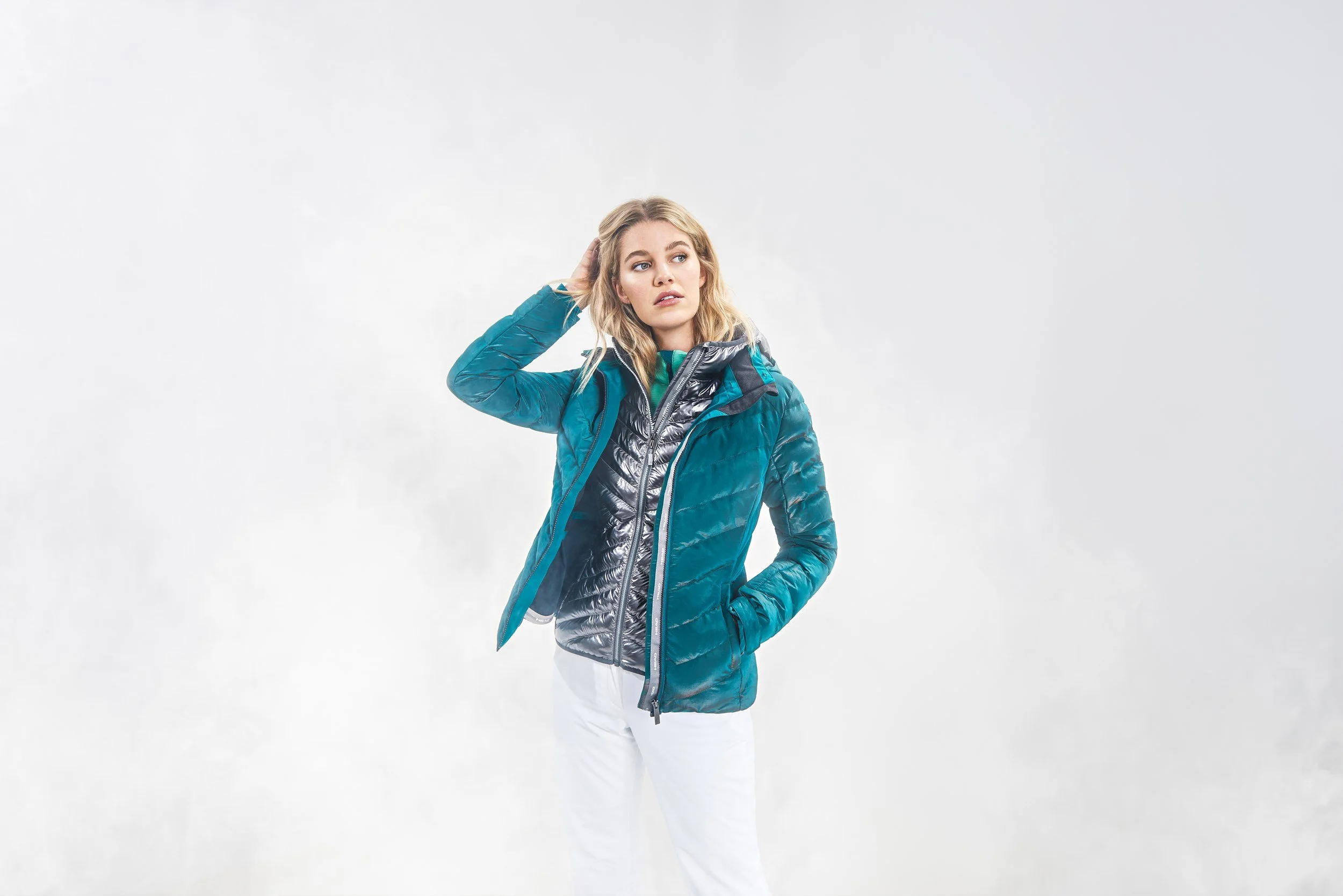 Frau in türkiser Daunenjacke im Nebel