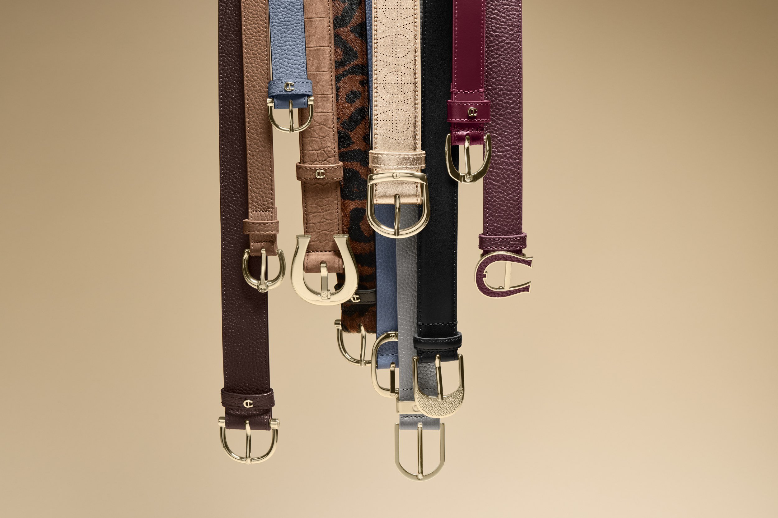 AIGNER Fall-Winter 2026: Gürtel-Sortiment hängend vor beigem Grund