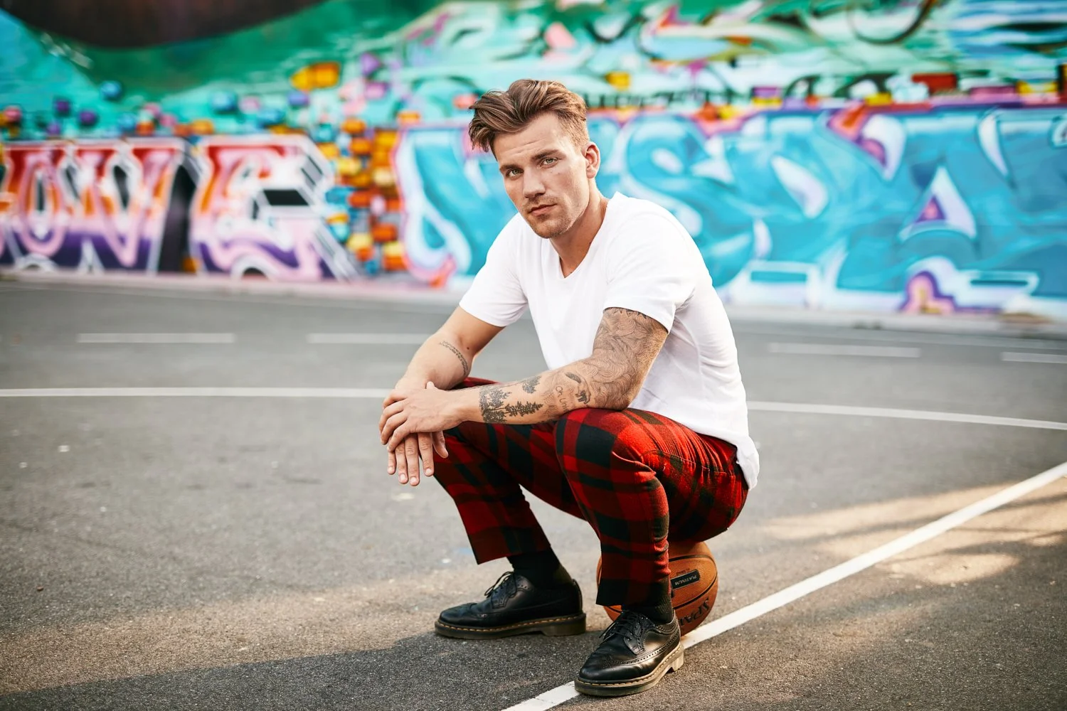 Mann in weißem Shirt und roter Karohose vor buntem Graffiti, #Alcinastyle Kampagne für Alcina – Retusche Bildergut.