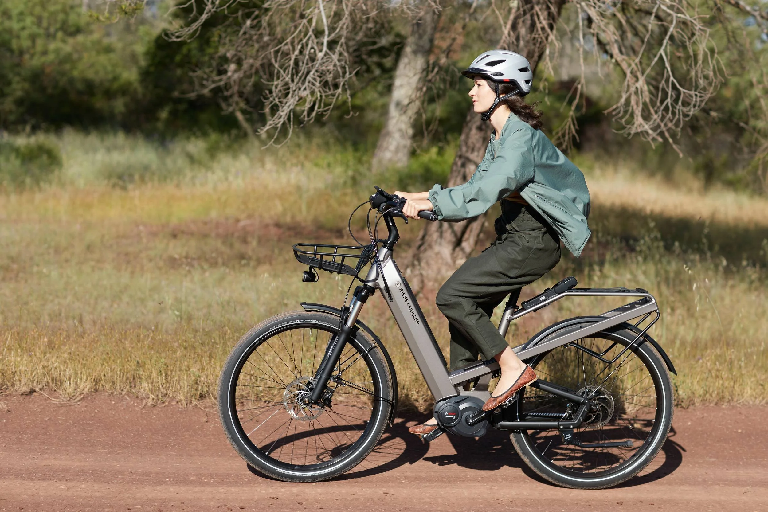 Fahrerin auf E-Bike im Profil auf rotem Schotterweg
