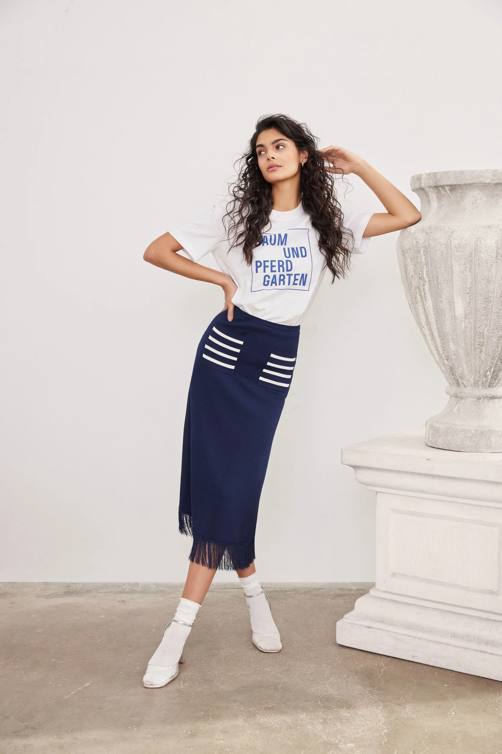 Modehaus Zinser Frühjahr-Sommer 2024: Shirt mit Schriftprint zu marineblauem Rock, weiße Socken in Sandalen