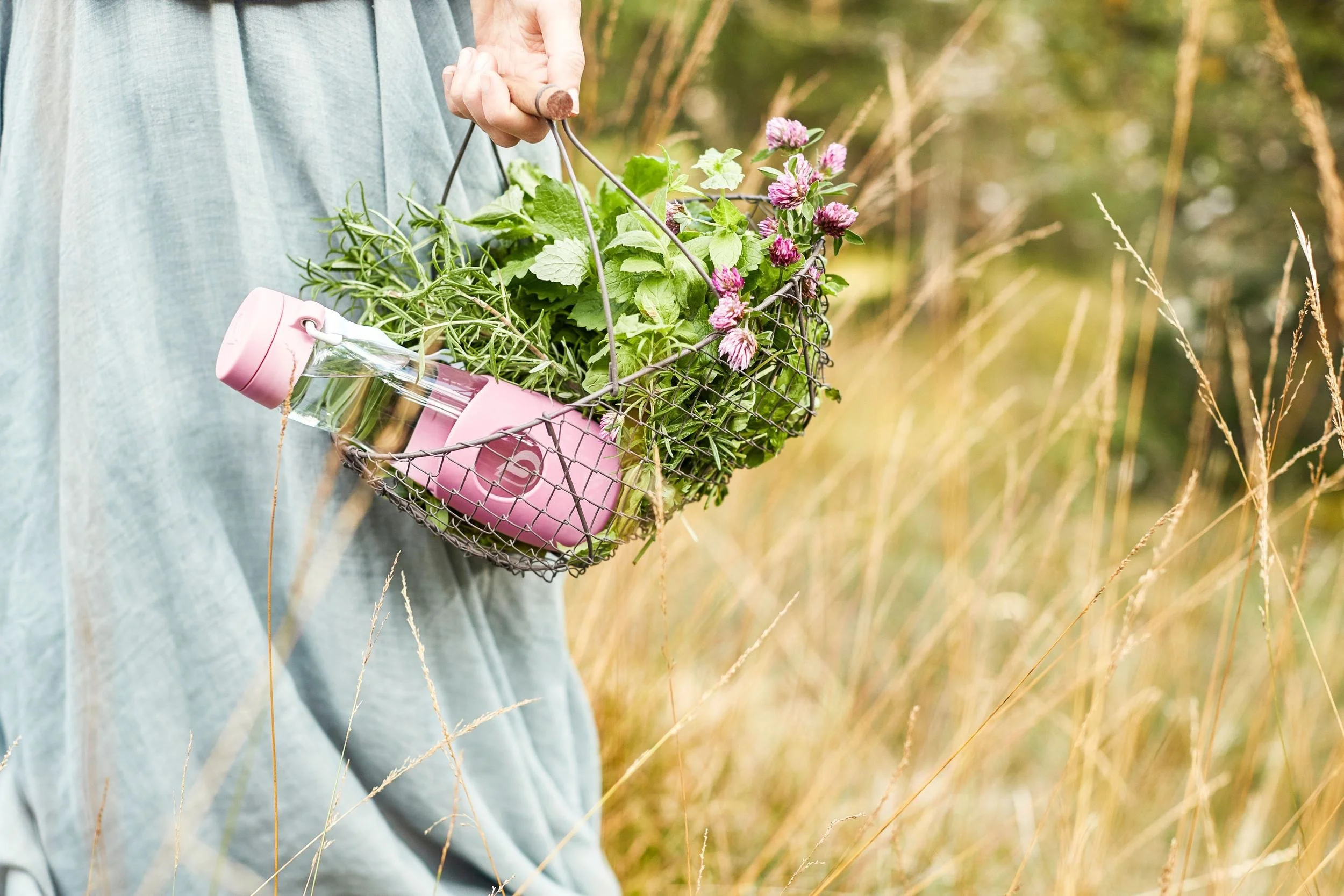 Blumenkorb mit pinker BWT-Trinkflasche im Almgras