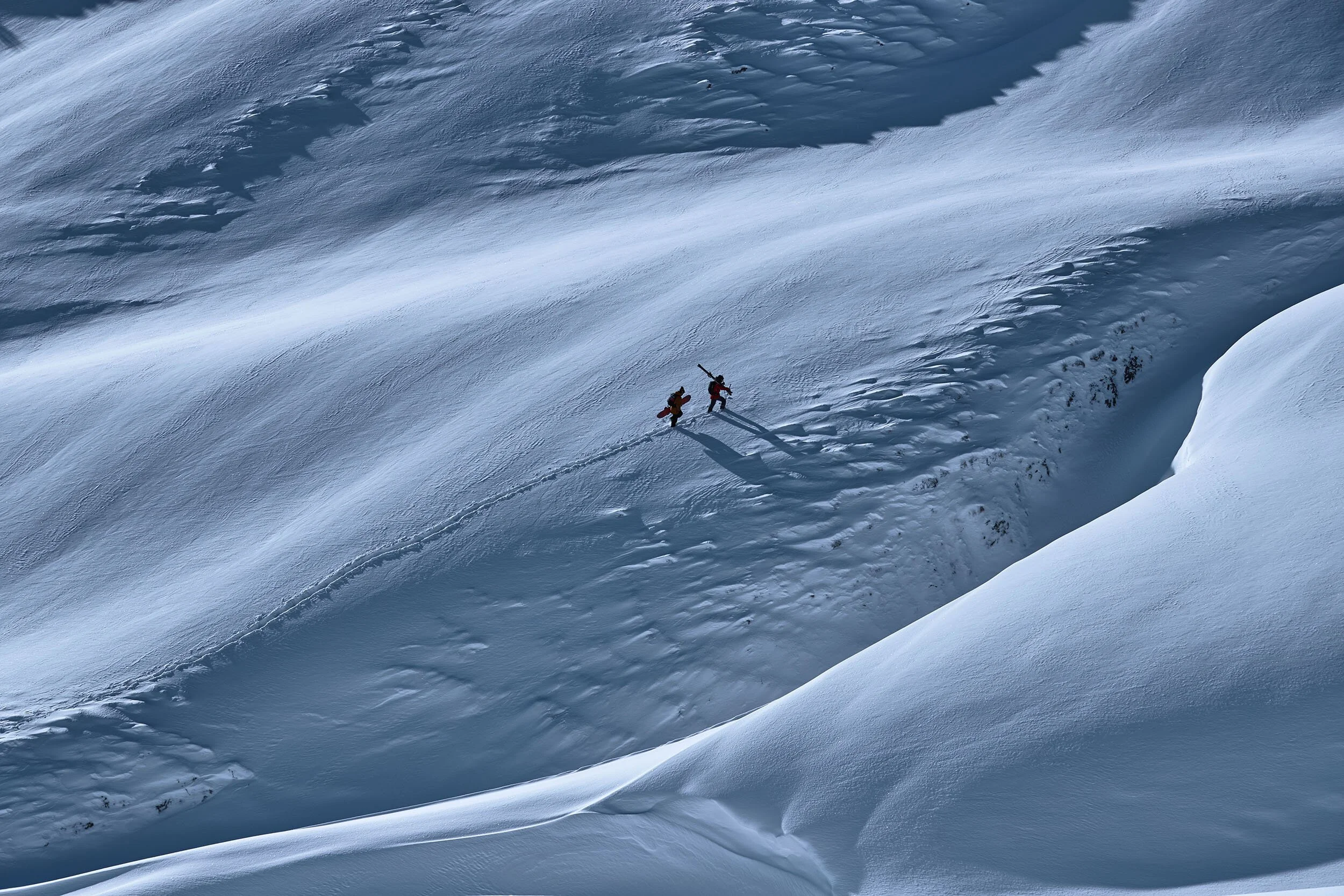 Zwei winzige Wintersportler auf weiter verschneiter Bergflanke, Fall-Winter-Kampagne für Buff – Retusche Bildergut.