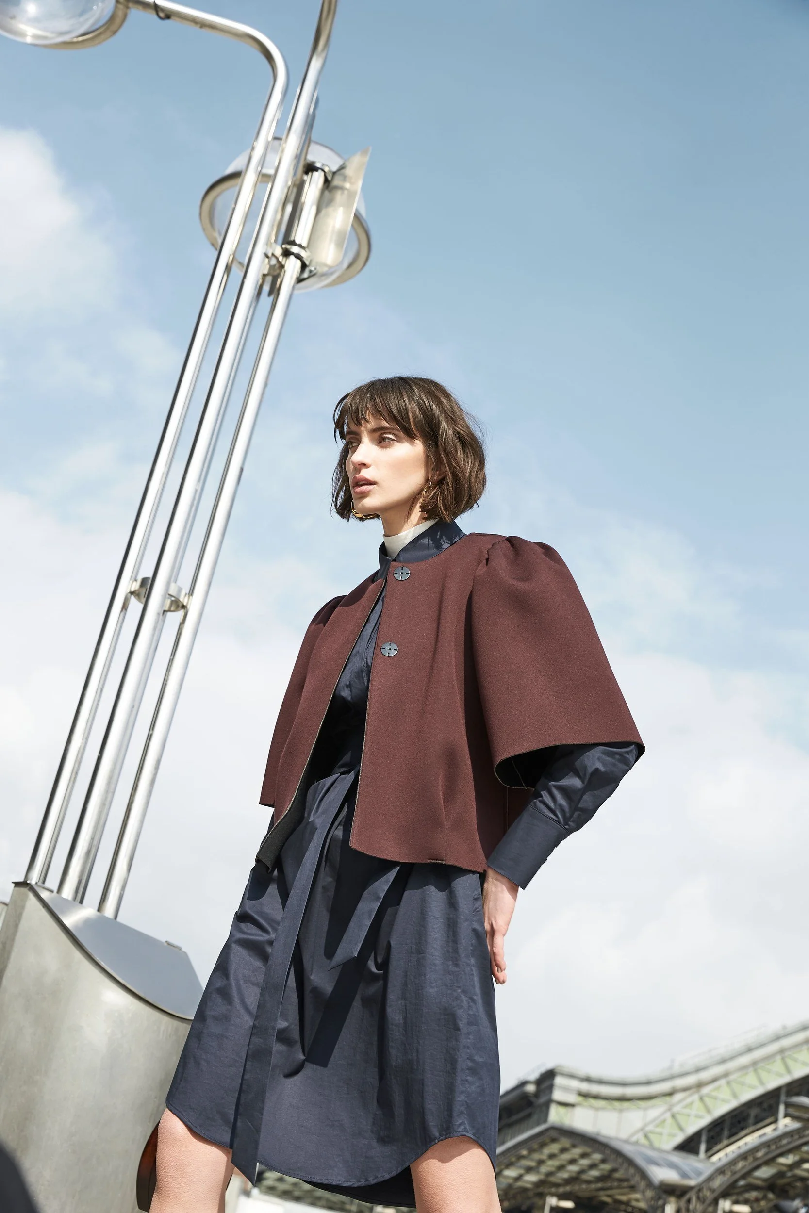 Hellmuth Lookbook 2019: brauner Cape-Blazer über blauem Kleid, Look KIM vor freiem Himmel