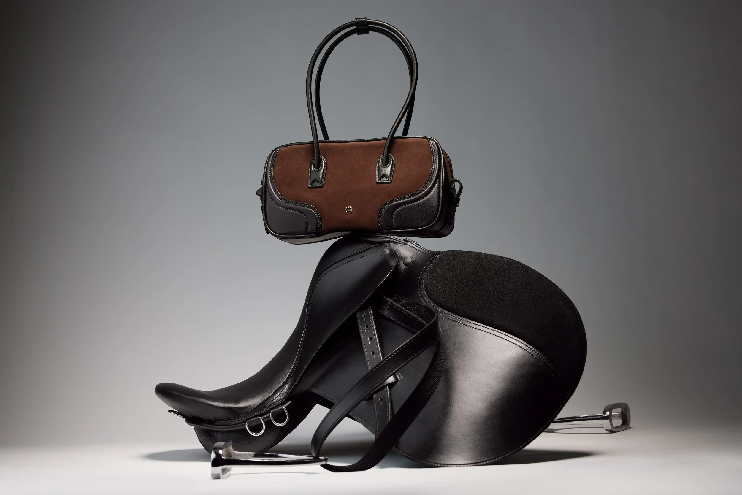 AIGNER Fall-Winter 2026: schwarze Handtasche auf einem Sattel, Reiterwelt-Still-Life